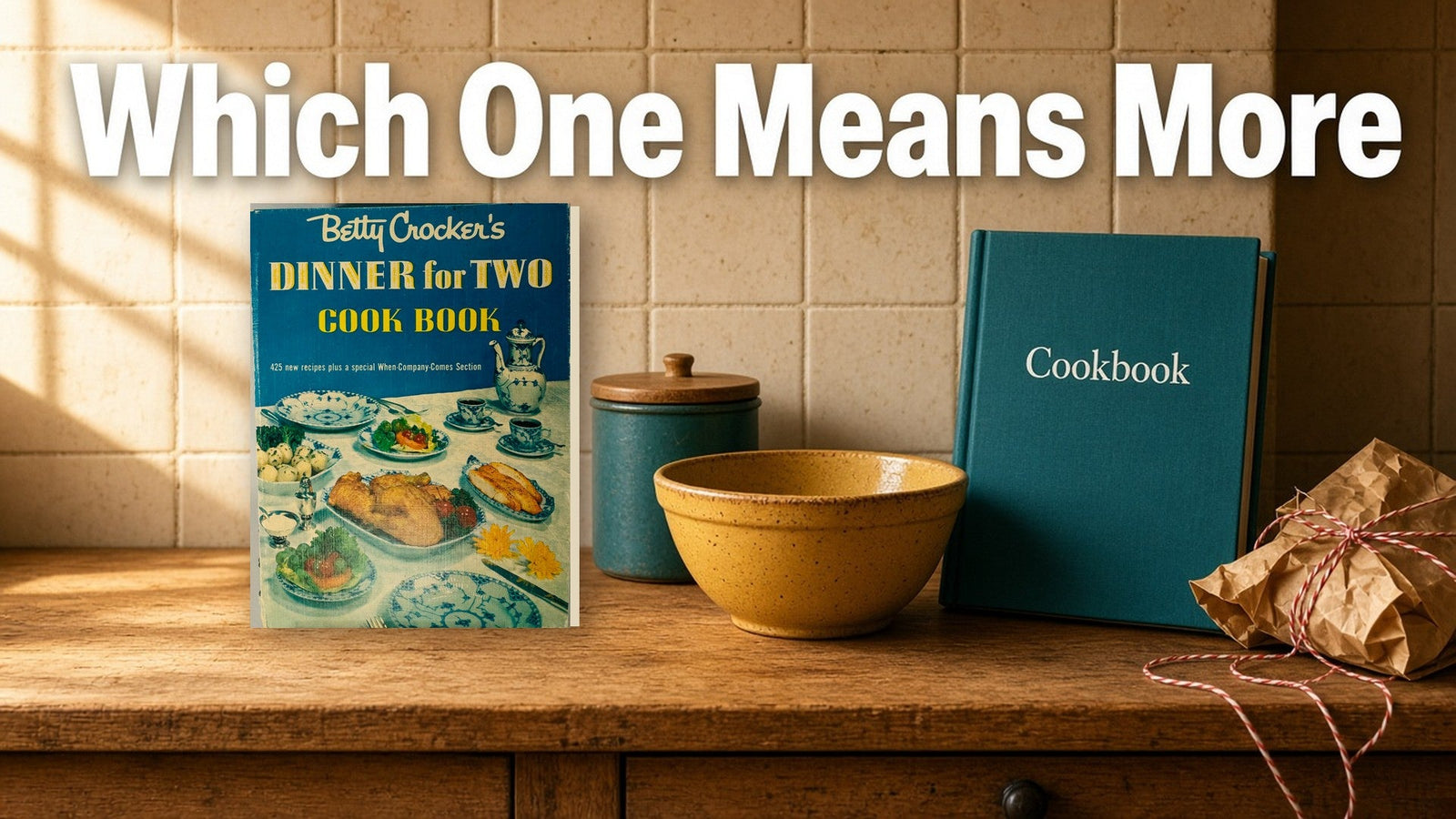 A vintage Betty Crocker's Dinner for Two Cook Book with its blue cover standing on a warm wood kitchen counter beside a new teal cookbook, a mustard mixing bowl and kraft paper tied with twine.