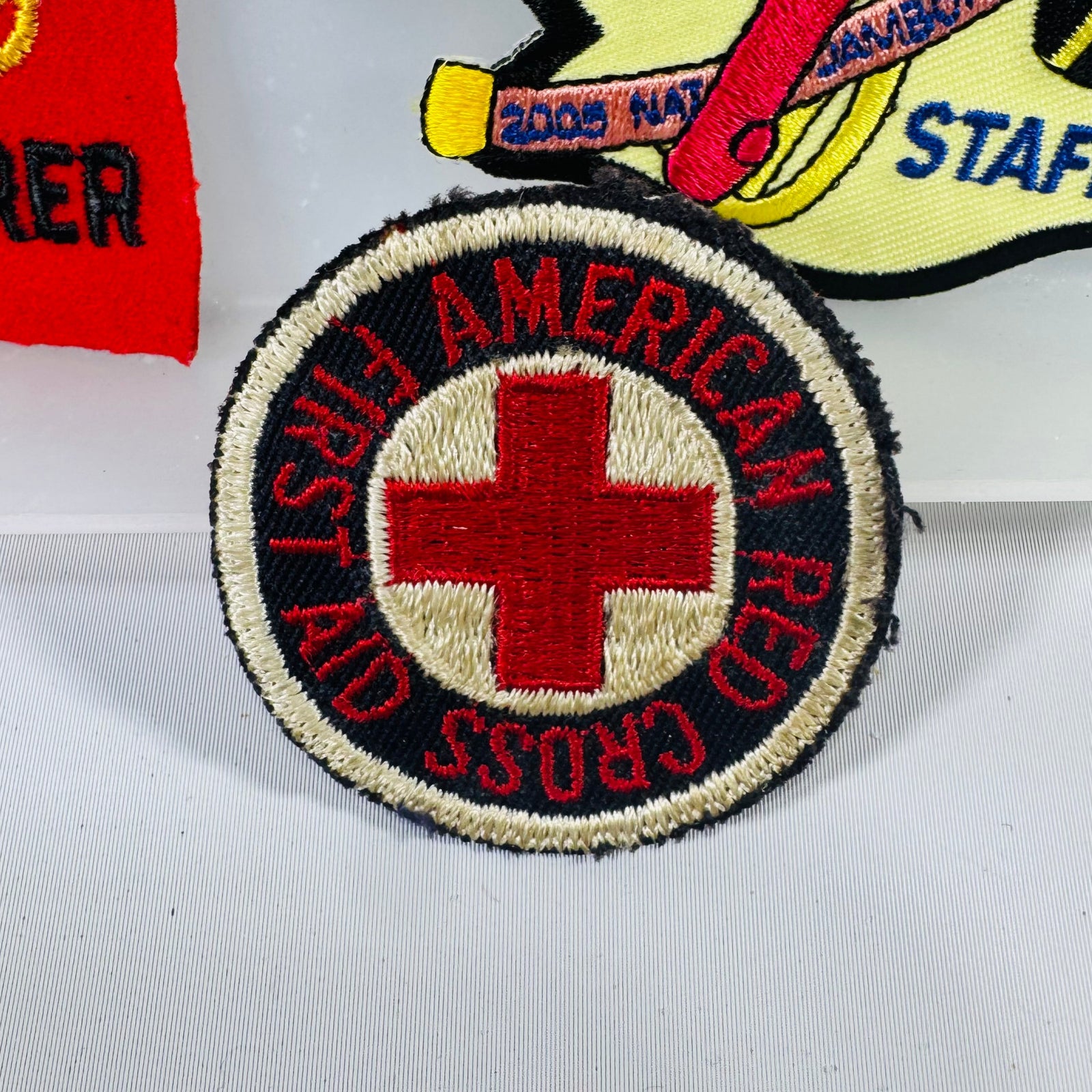 Collection of patches including a Red Cross patch on a white background