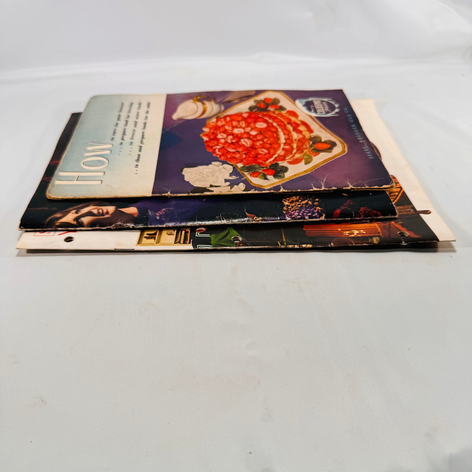 Three Sears Coldspot manuals stacked, showing cover edge wear