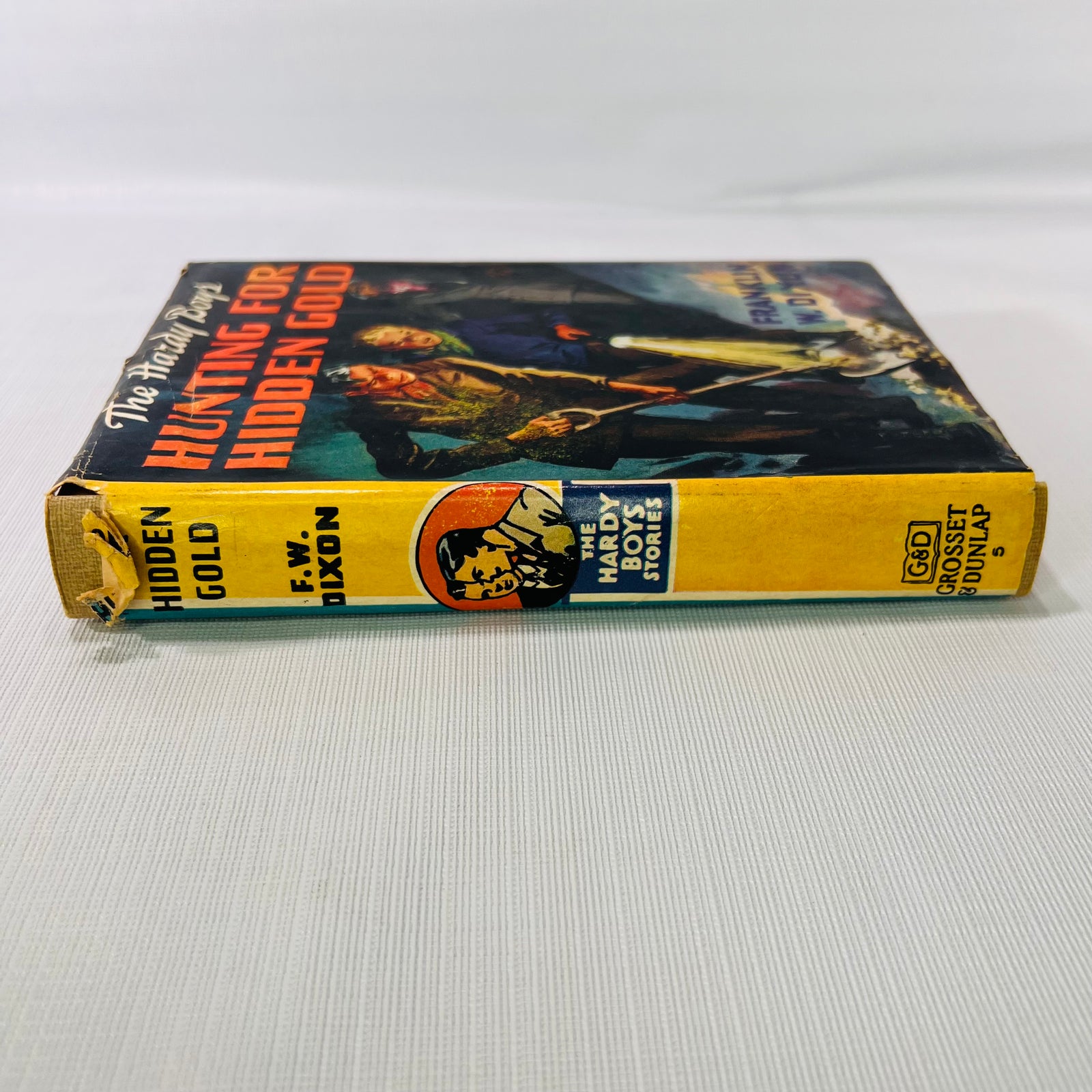 Dust jacket spine of The Hardy Boys Hunting for Hidden Gold, chipped at the top