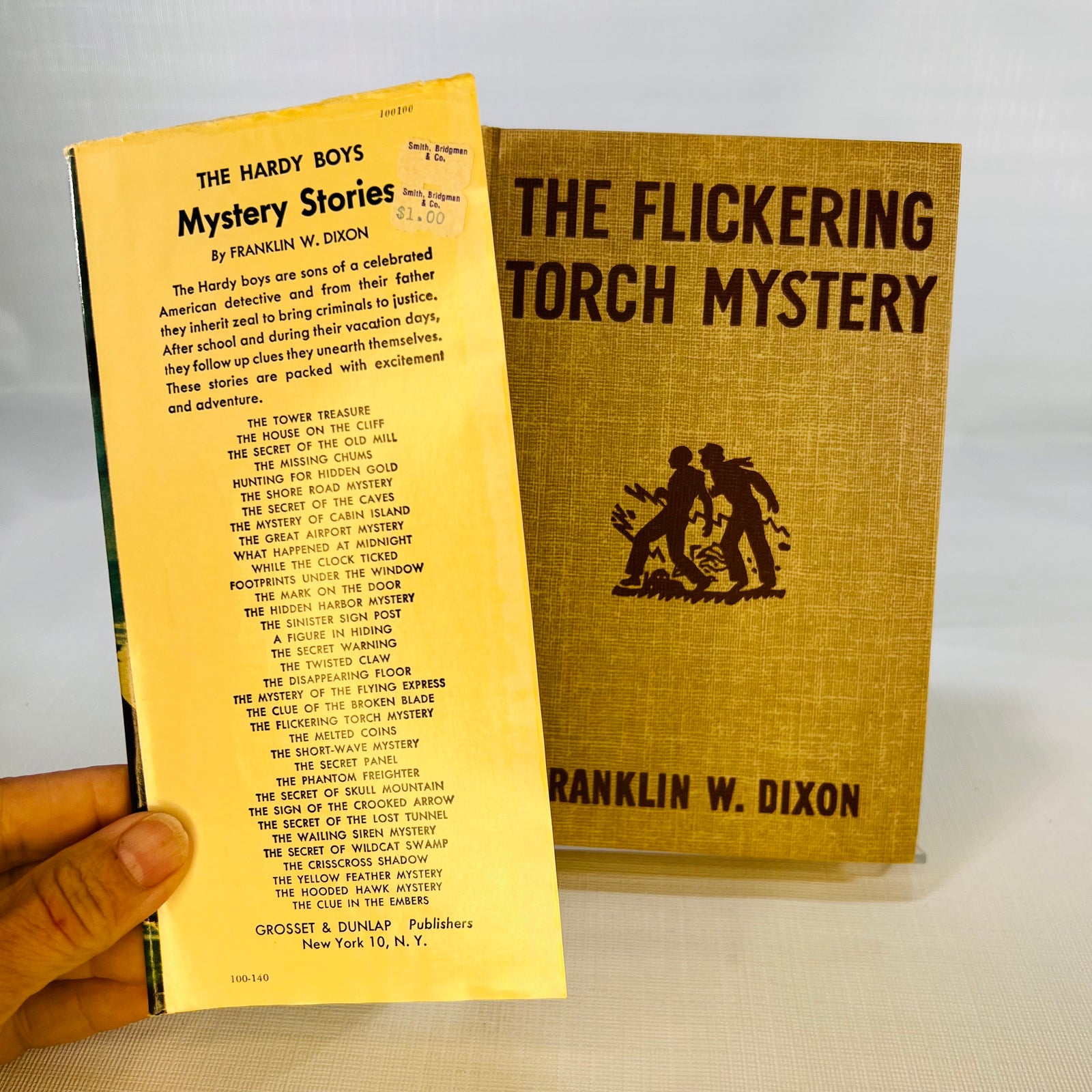 Jacket flap listing Hardy Boys Mystery Stories beside the tan cloth cover, Flickering Torch Mystery