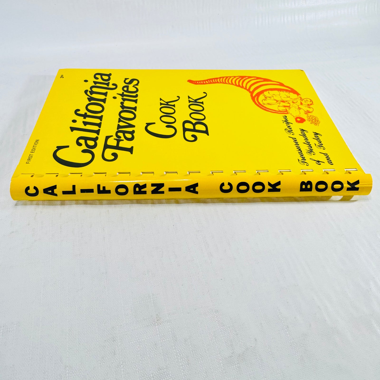 Book flat with the yellow comb spine reading California Cook Book