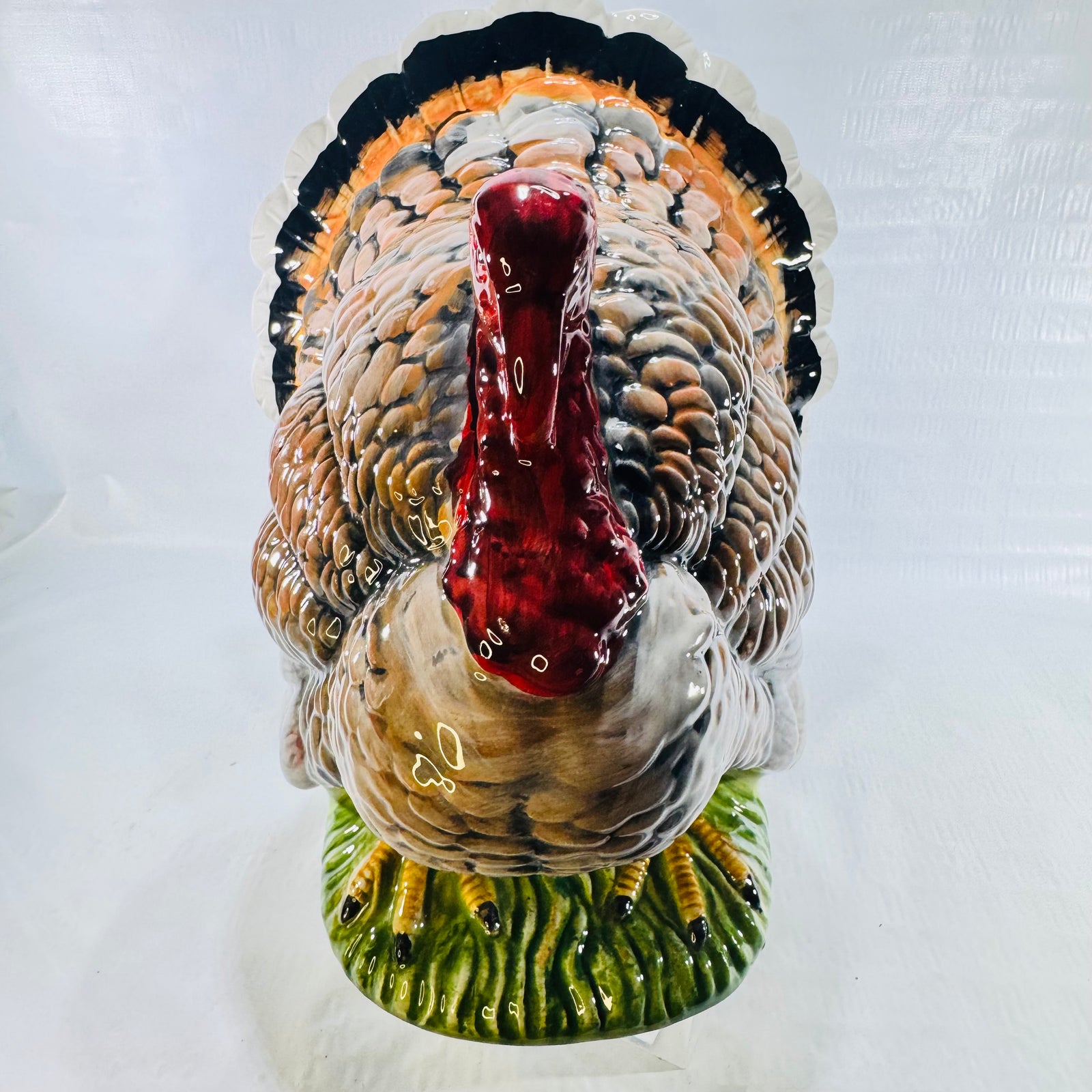 Front view of a standing ceramic turkey with red wattle and green grass base