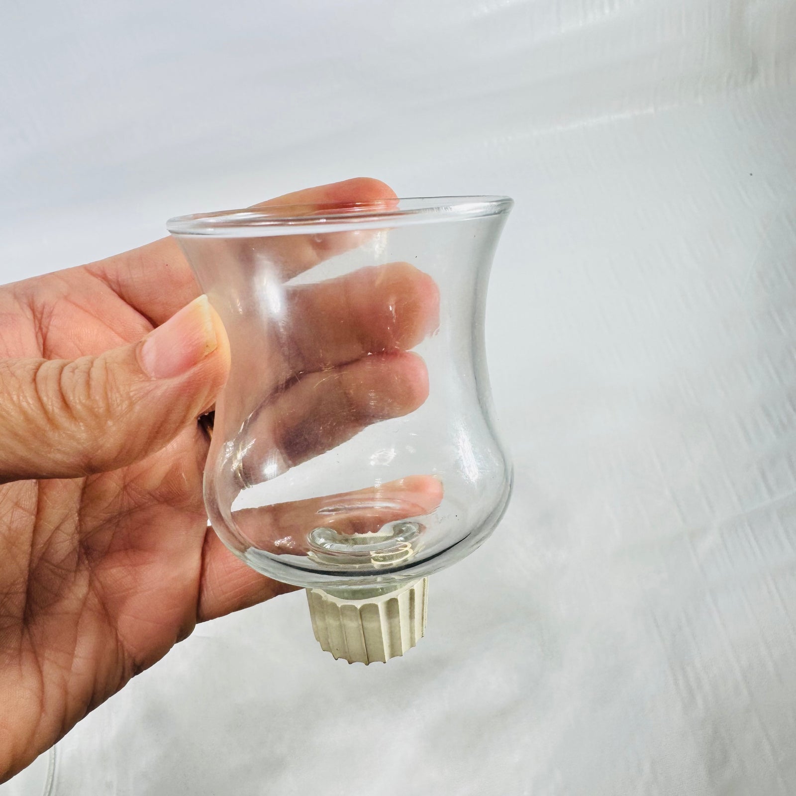 Small clear glass votive cup with a tan ribbed rubber gripper on the peg.