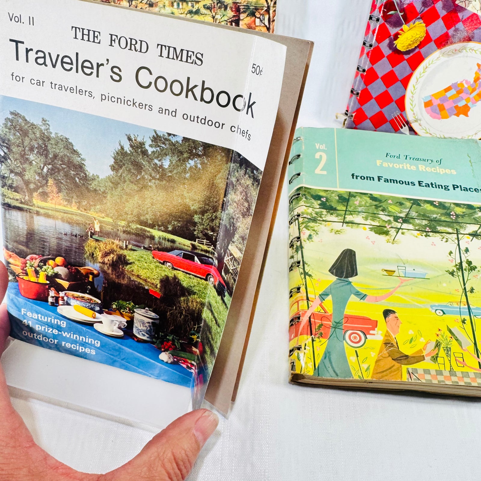 Traveler's Cookbook held up above Volume 2 lying flat