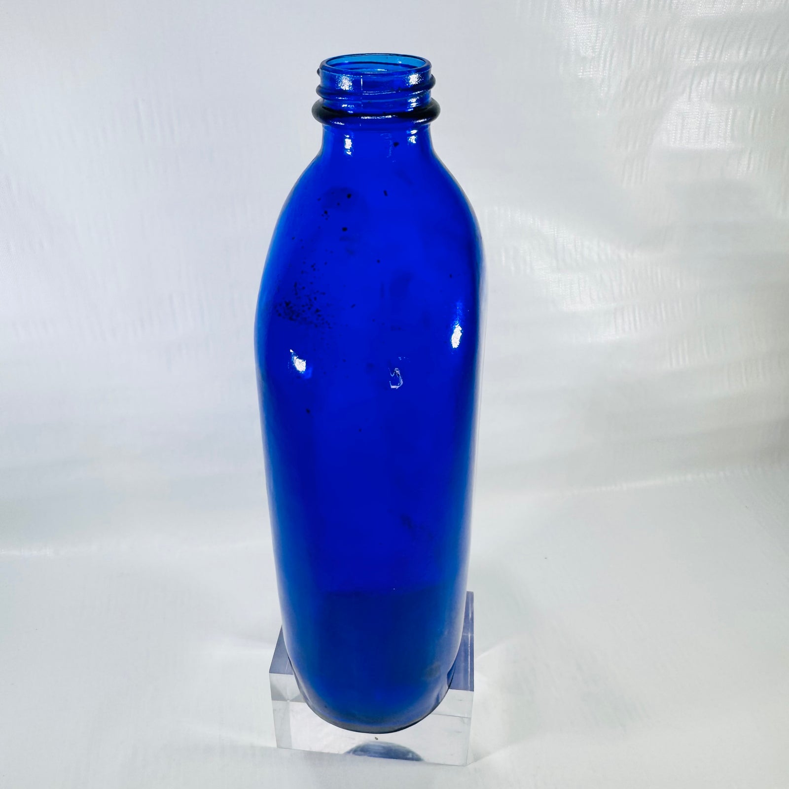 Other side of the cobalt bottle with dark specks visible inside the shoulder.
