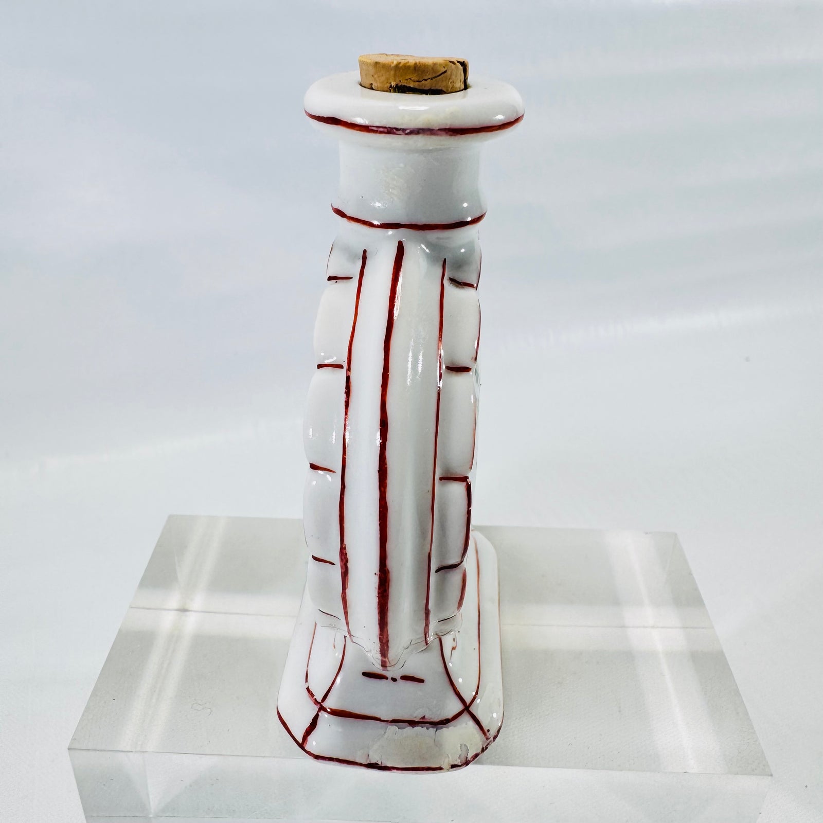 Side view of the porcelain moon flask bottle showing molded ribbed sides traced in red and the pedestal base.