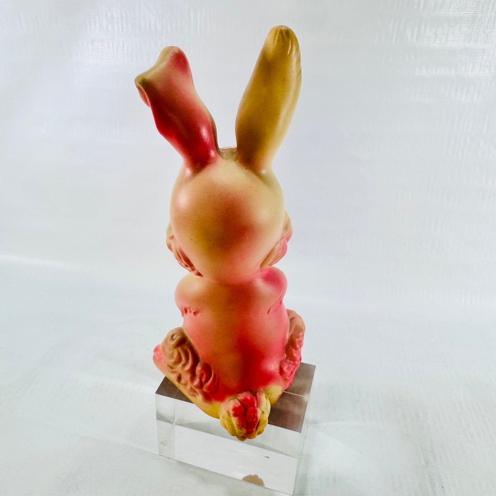 Back of the rabbit showing the cream head, one pink ear, one tan ear, and the molded curly tail.