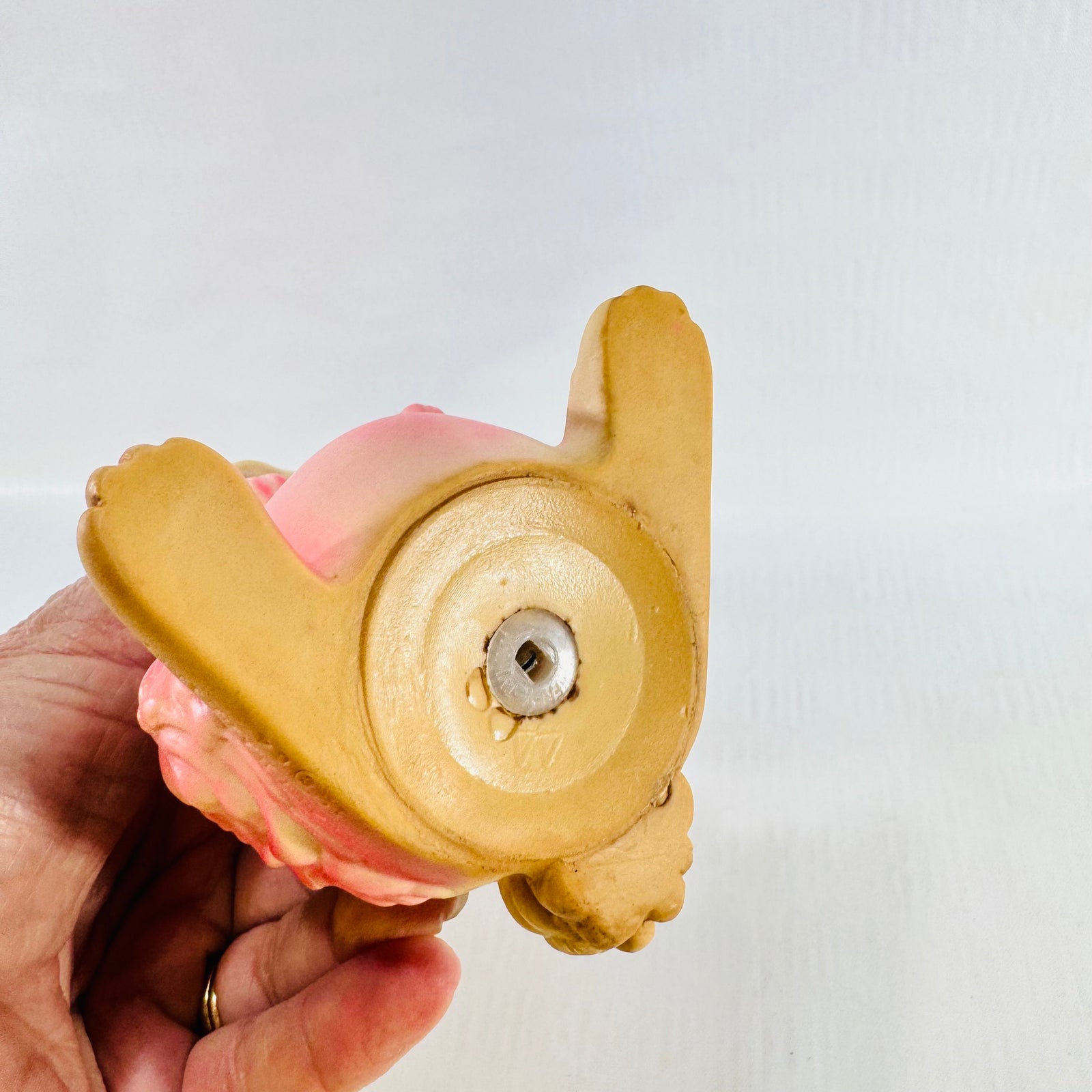 Underside of the rabbit showing the round metal squeaker set in the center of the tan base.