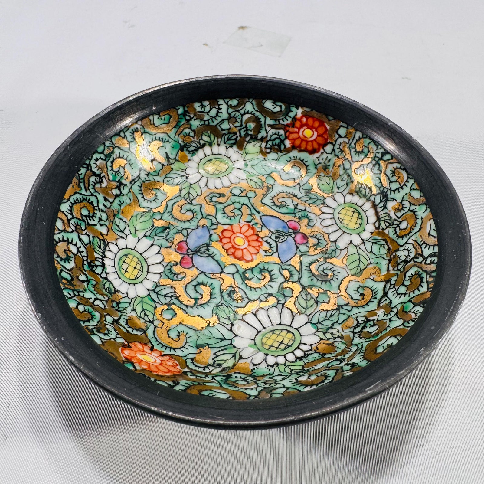Angled close-up of the interior rim of the cloisonné bowl, highlighting gold outlining on floral enamel work.