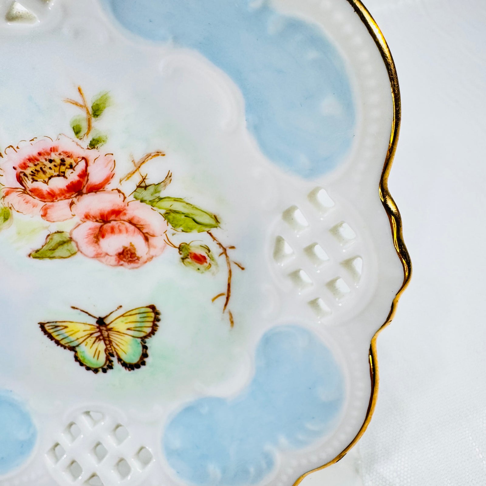 Close up of the painted roses, butterfly, and pierced lattice panel with the gold edge.