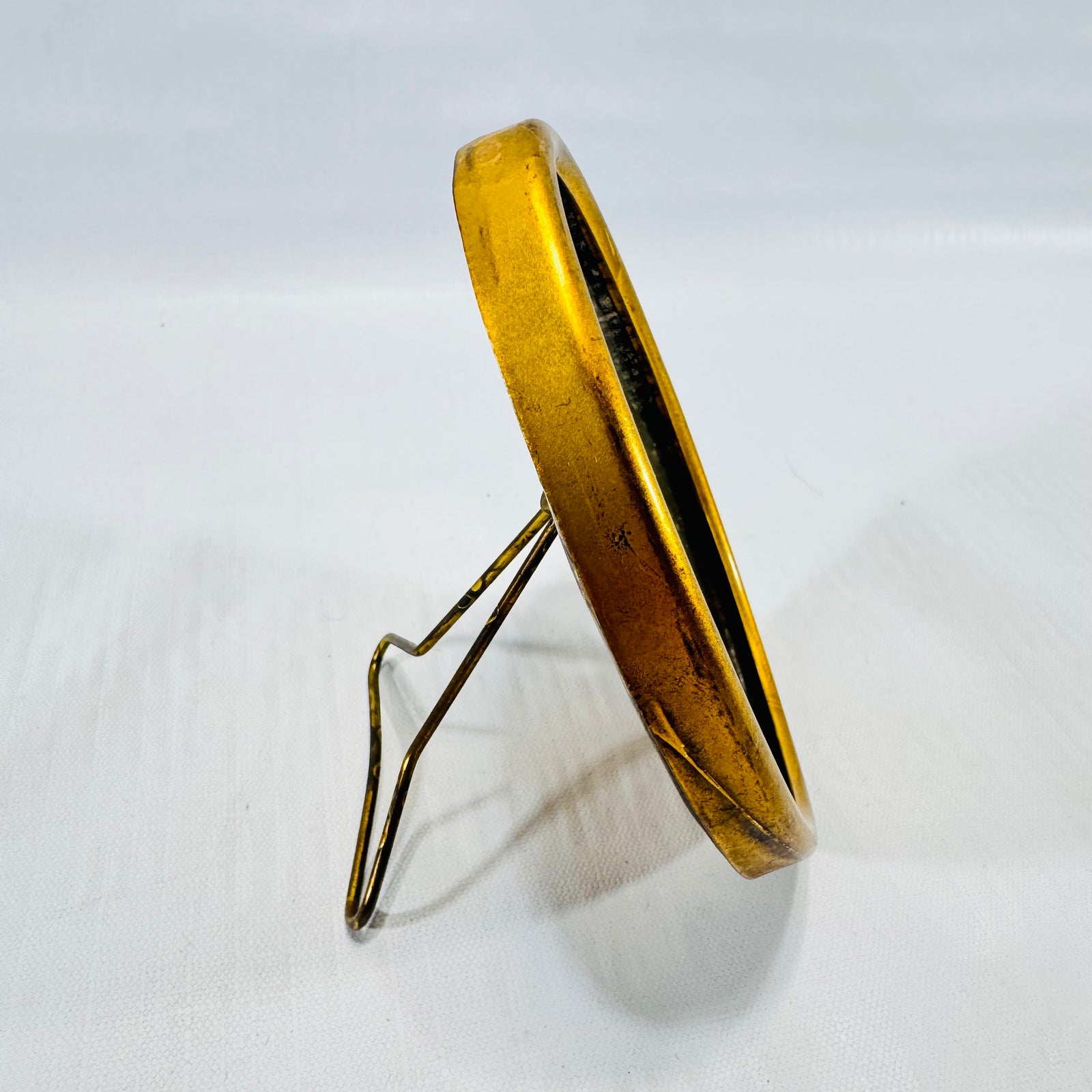 Other side view of the gold tone oval frame and wire stand.