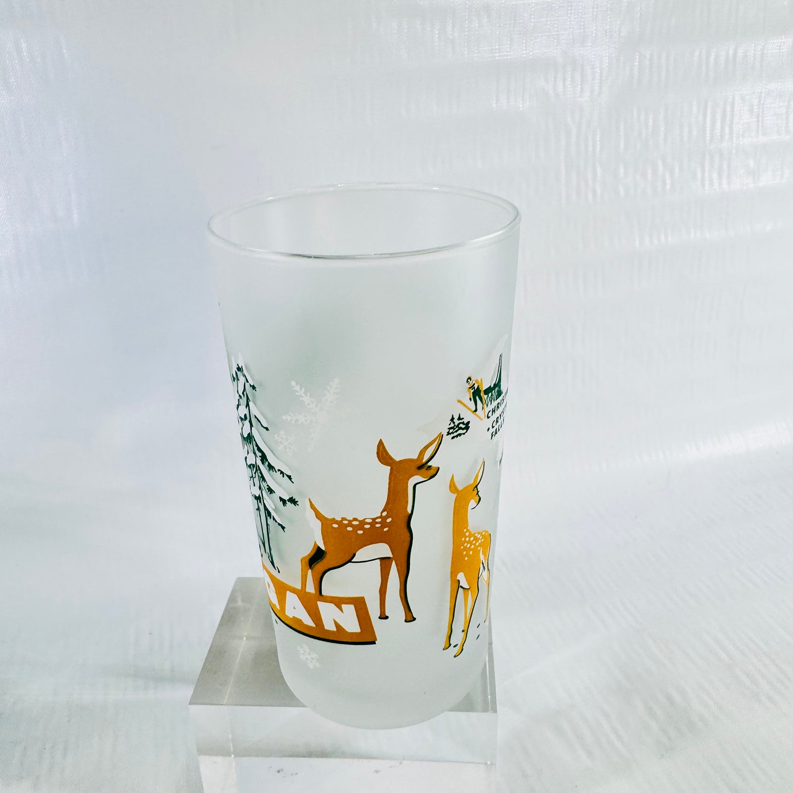 Three quarter view of the frosted tumbler showing two white-tailed deer fawns and snowy pines on the side.