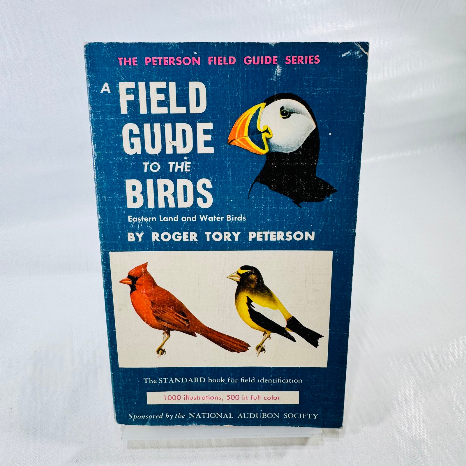 Blue front cover of A Field Guide to the Birds by Roger Tory Peterson, with puffin, cardinal, and goldfinch illustrations and visible rubbing.