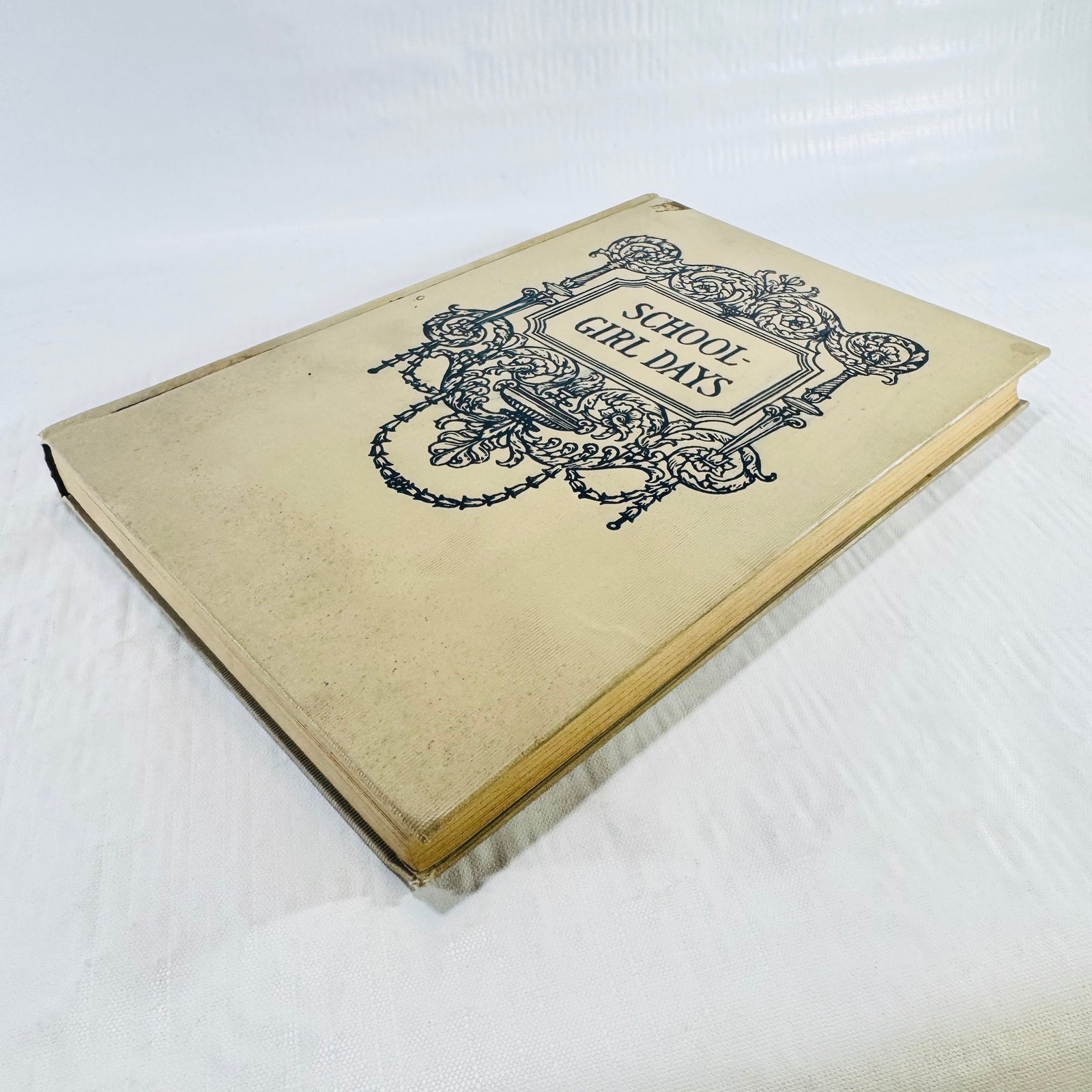 Front cover laid flat showing staining and age spots on the cream cloth