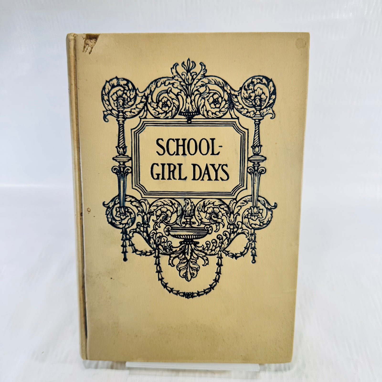 Cream ribbed cloth front cover with dark blue scroll frame and a small chip