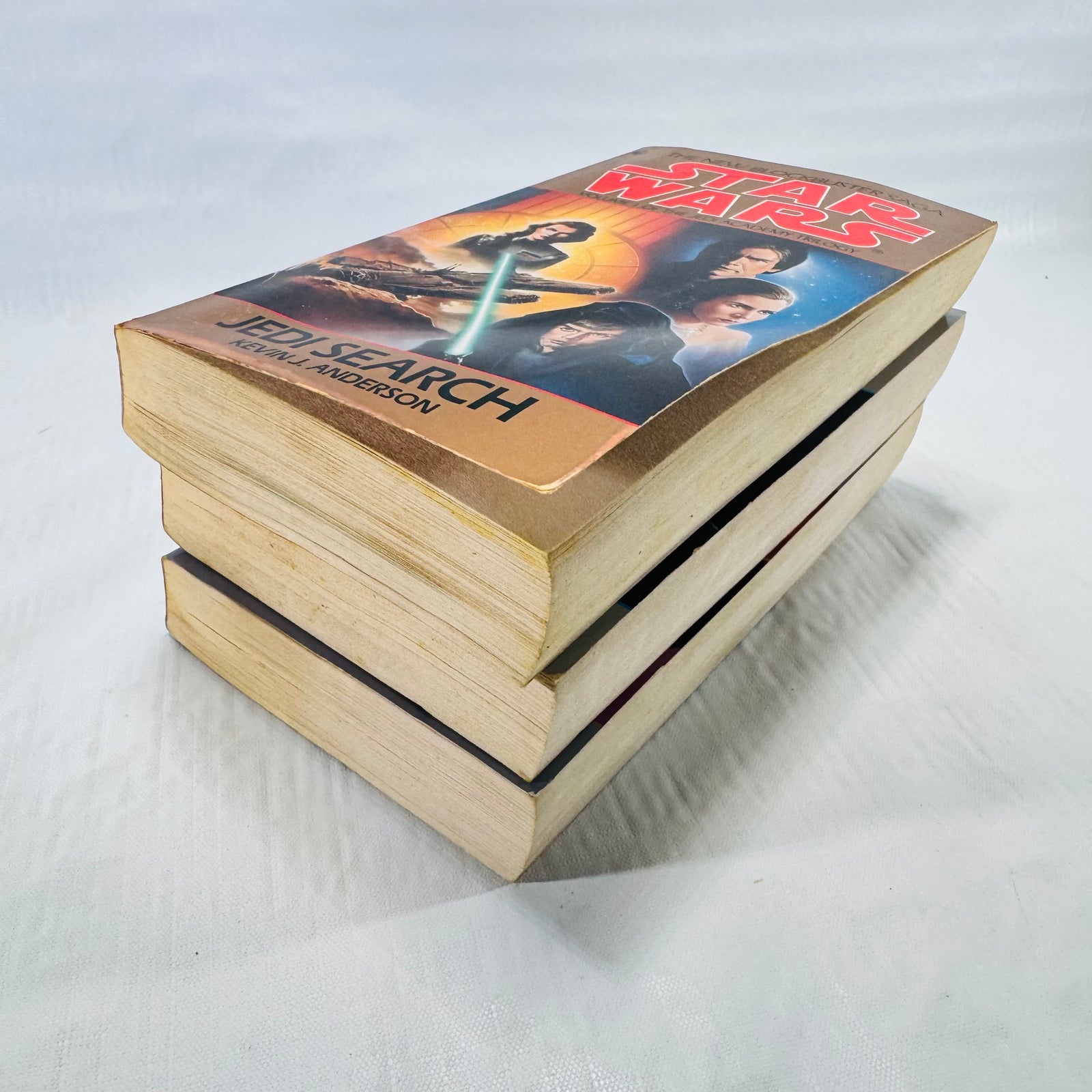 Page edges of the three Jedi Academy Trilogy paperbacks, toned with age, with Jedi Search on top.