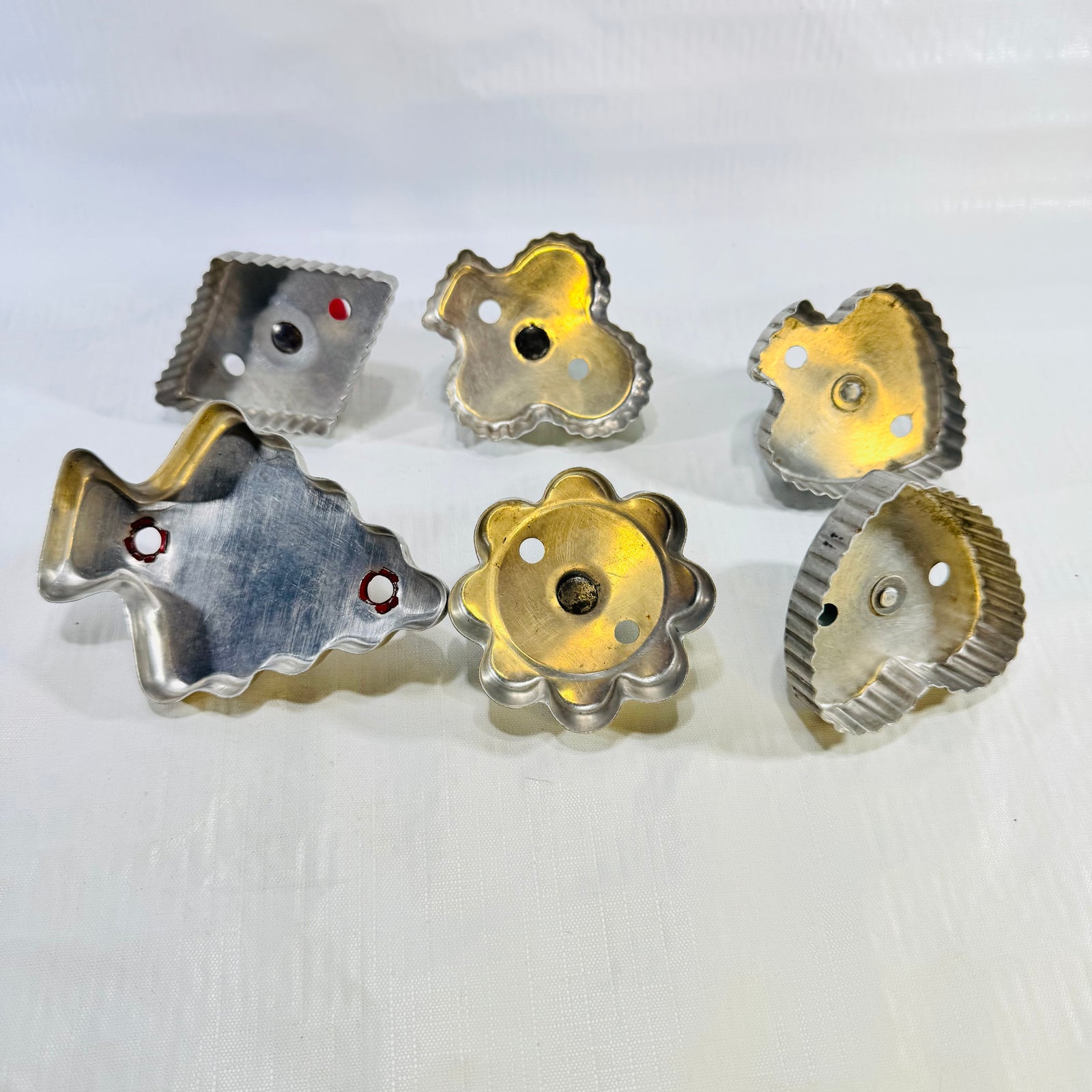 Undersides of the six aluminum cookie cutters showing cutting edges and air holes
