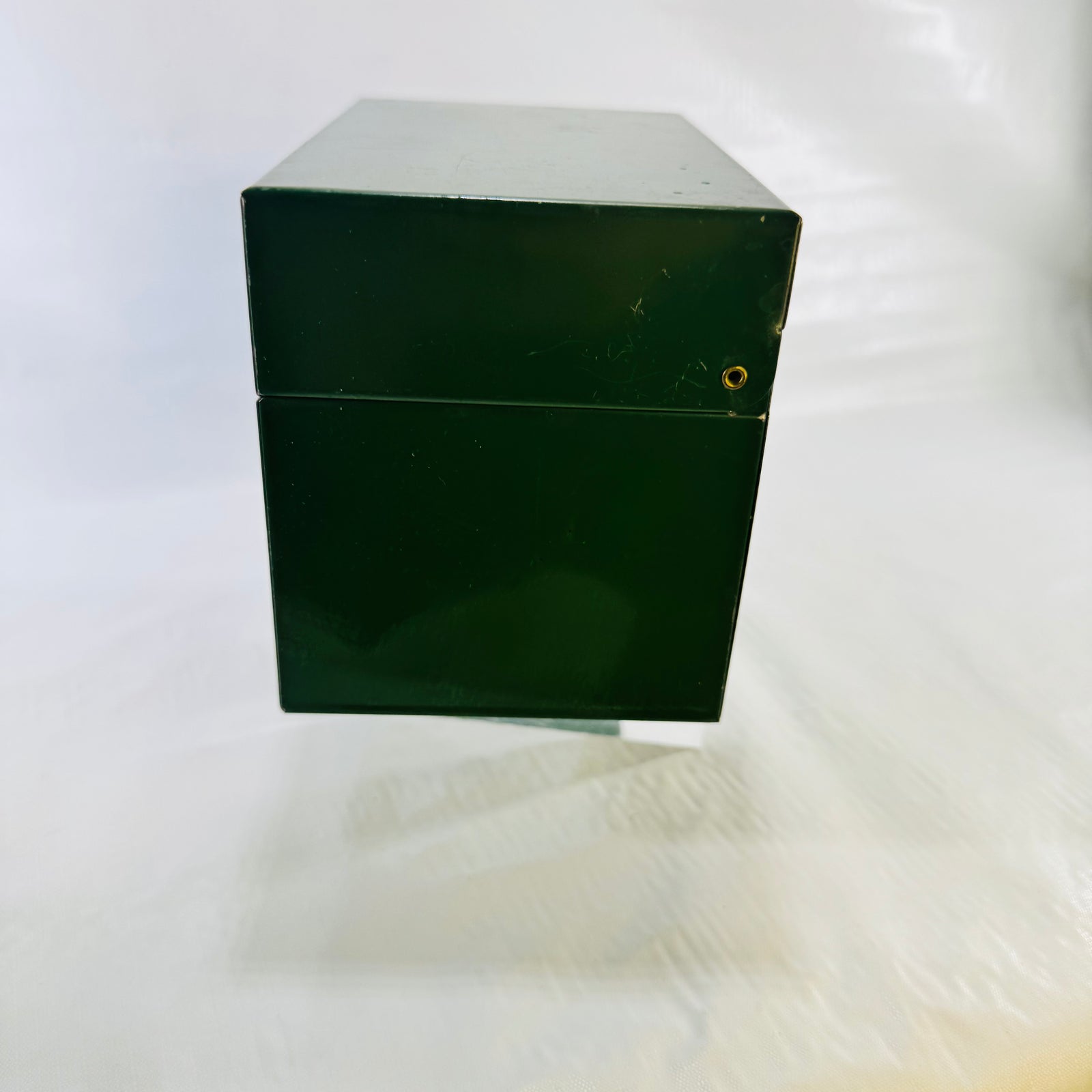 Side of the closed green metal recipe box showing the hinge rivet