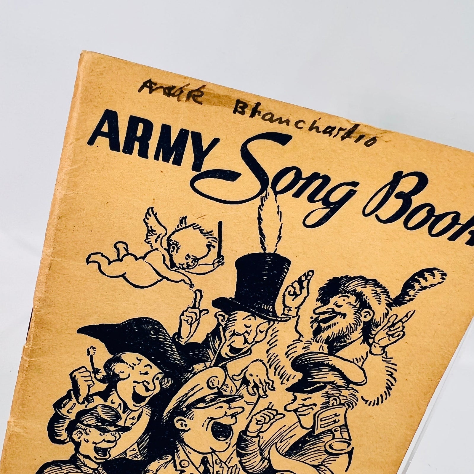 Close view of the Army Song Book 1941 cover art and handwritten name