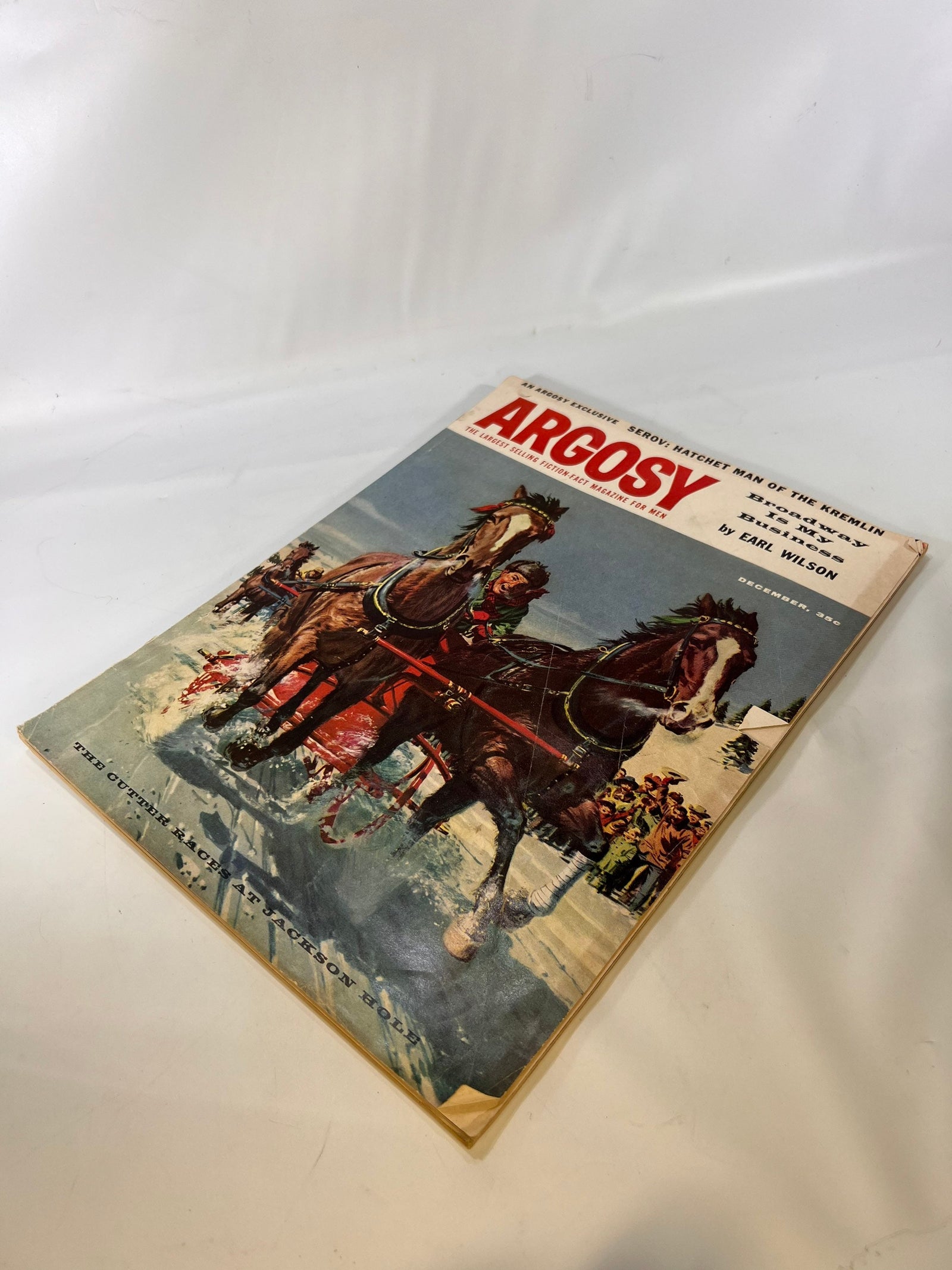 Argosy December 1957 lying at an angle, showing cover scuffs and corner dings