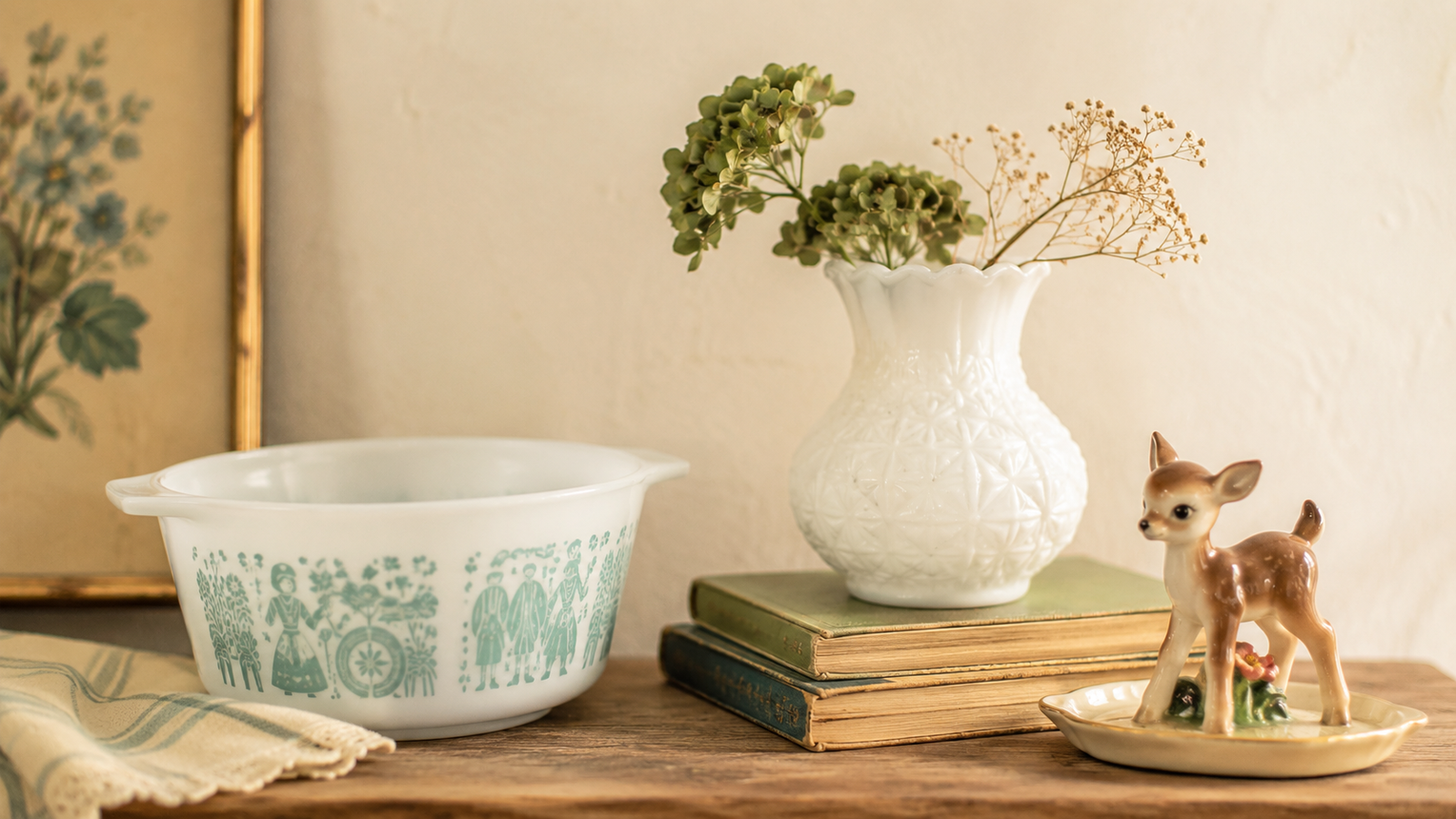  small still life of vintage Pyrex, milk glass, and a ceramic figure on a warm wood shelf.
