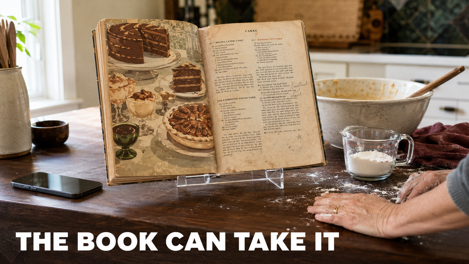 An open vintage cookbook propped on a clear acrylic stand on a kitchen counter, with a mixing bowl, scattered flour, and a pair of hands mid task beside it.