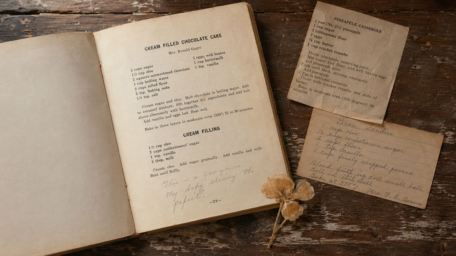 Open vintage church cookbook on a wood table with handwritten recipe notes, a clipping, and an old index card.