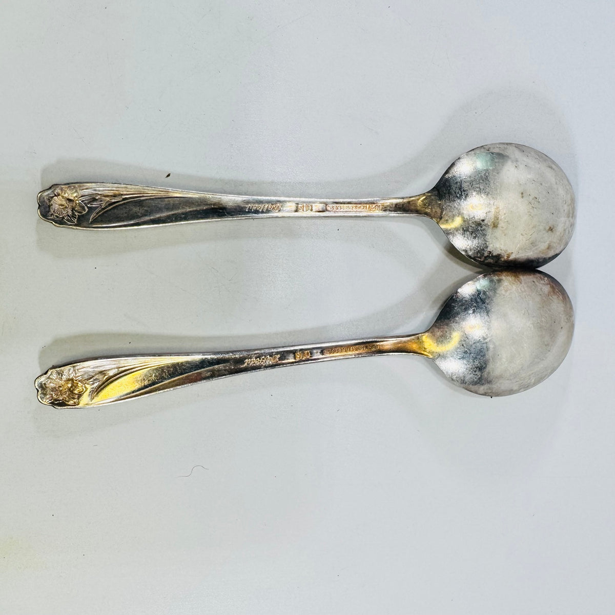 Back view of two 1847 Rogers Bros Daffodil silverplate soup spoons with marks