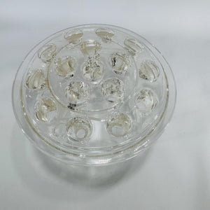 Clear round glass flower frog with multiple stem holes in a dome design, viewed from above