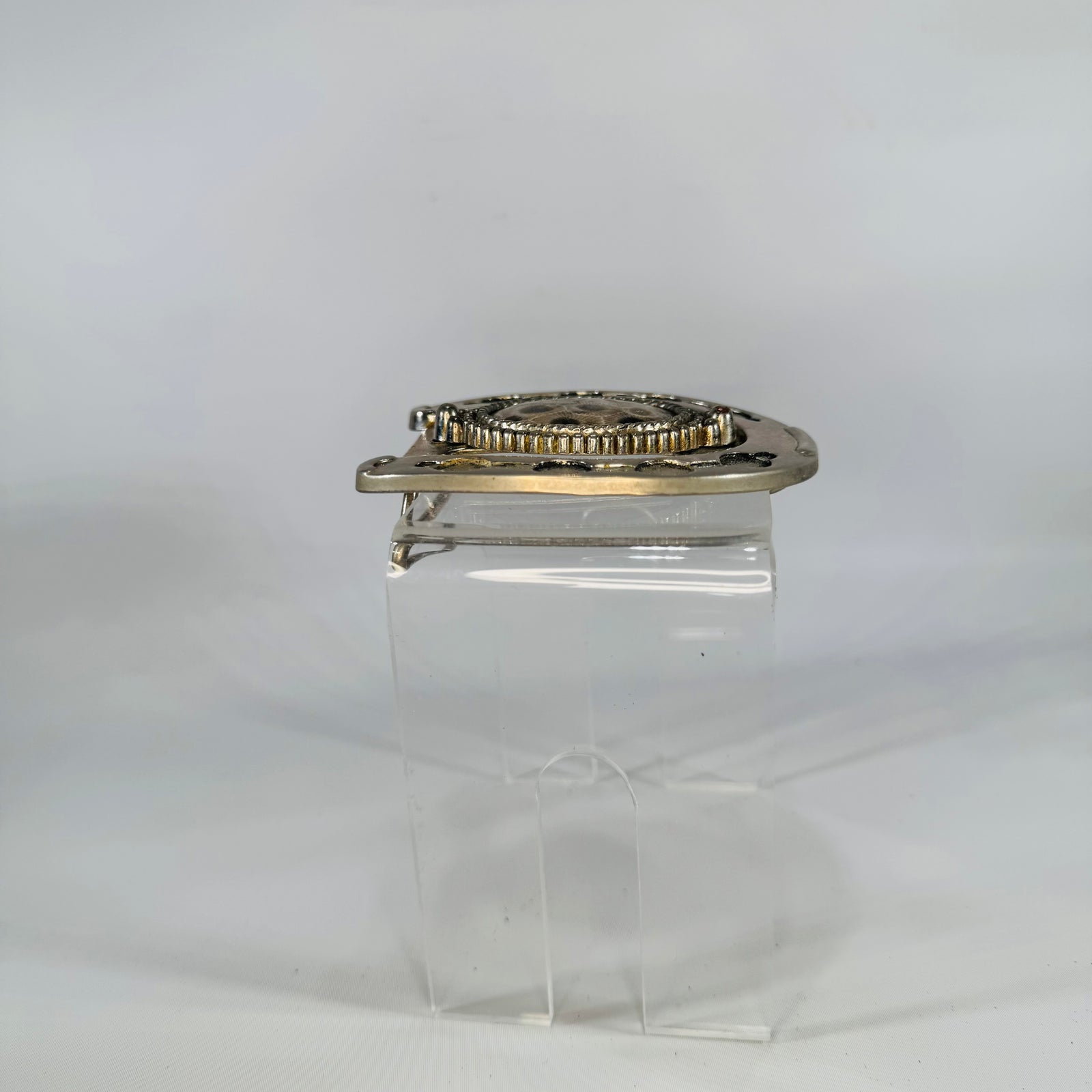 Decorative belt buckle with intricate design on a white background