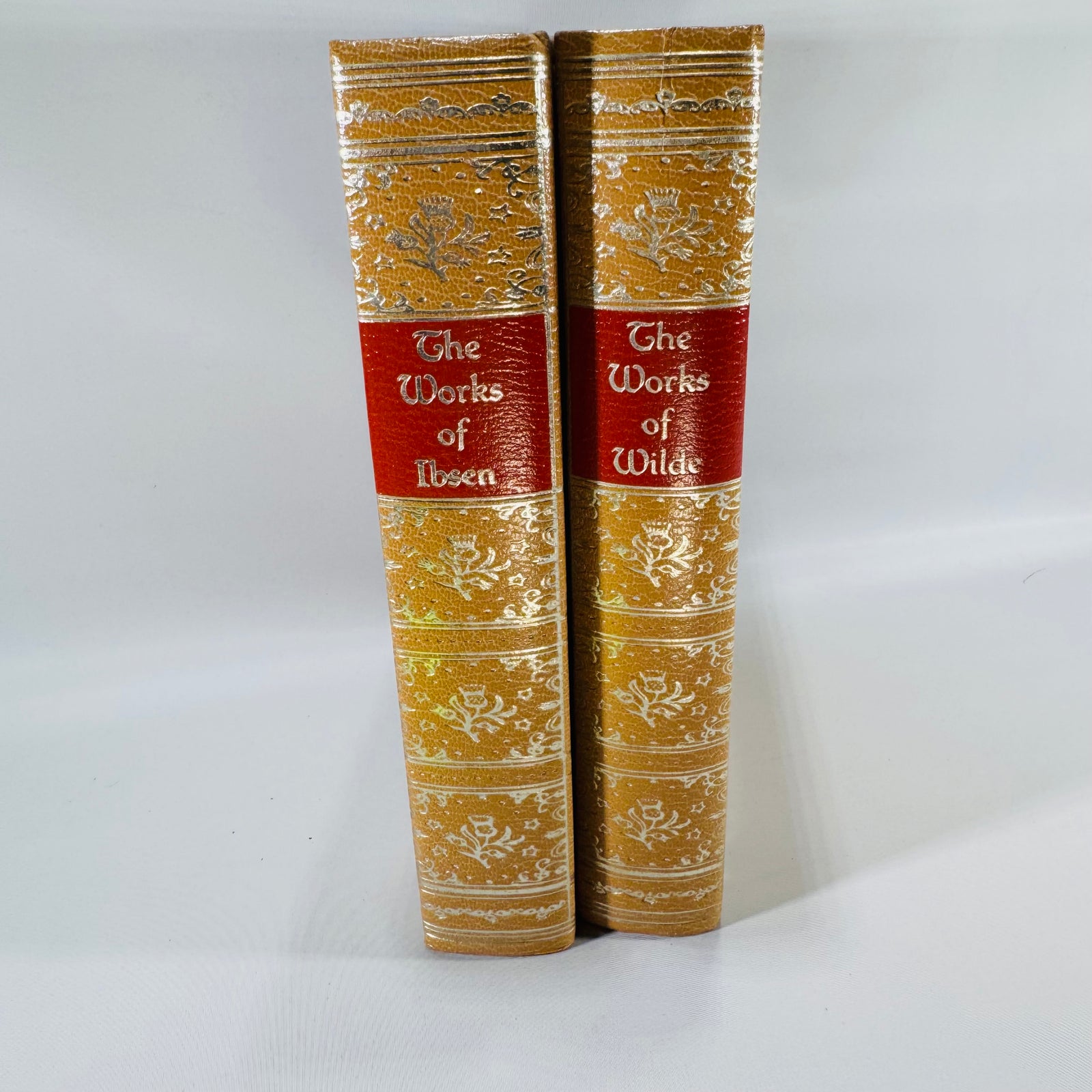 Two gold-bound books with red bands on a gray background