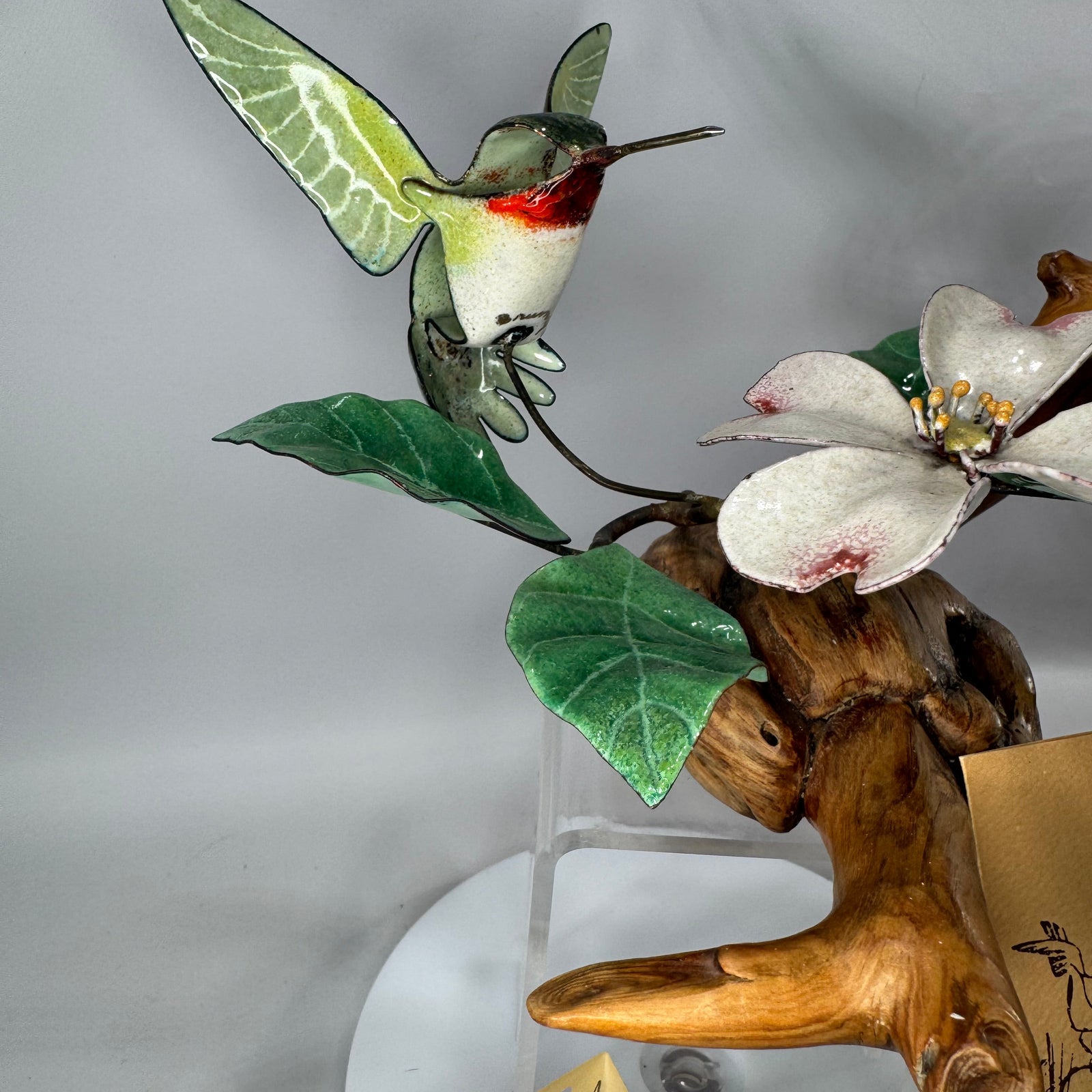 Norman and Judith Brumm ruby-throated hummingbird enamel-on-copper sculpture hovering over dogwood blossom on a natural burl wood base, signed.sculpture hovering over dogwood blossom on a natural burl wood base, signed.