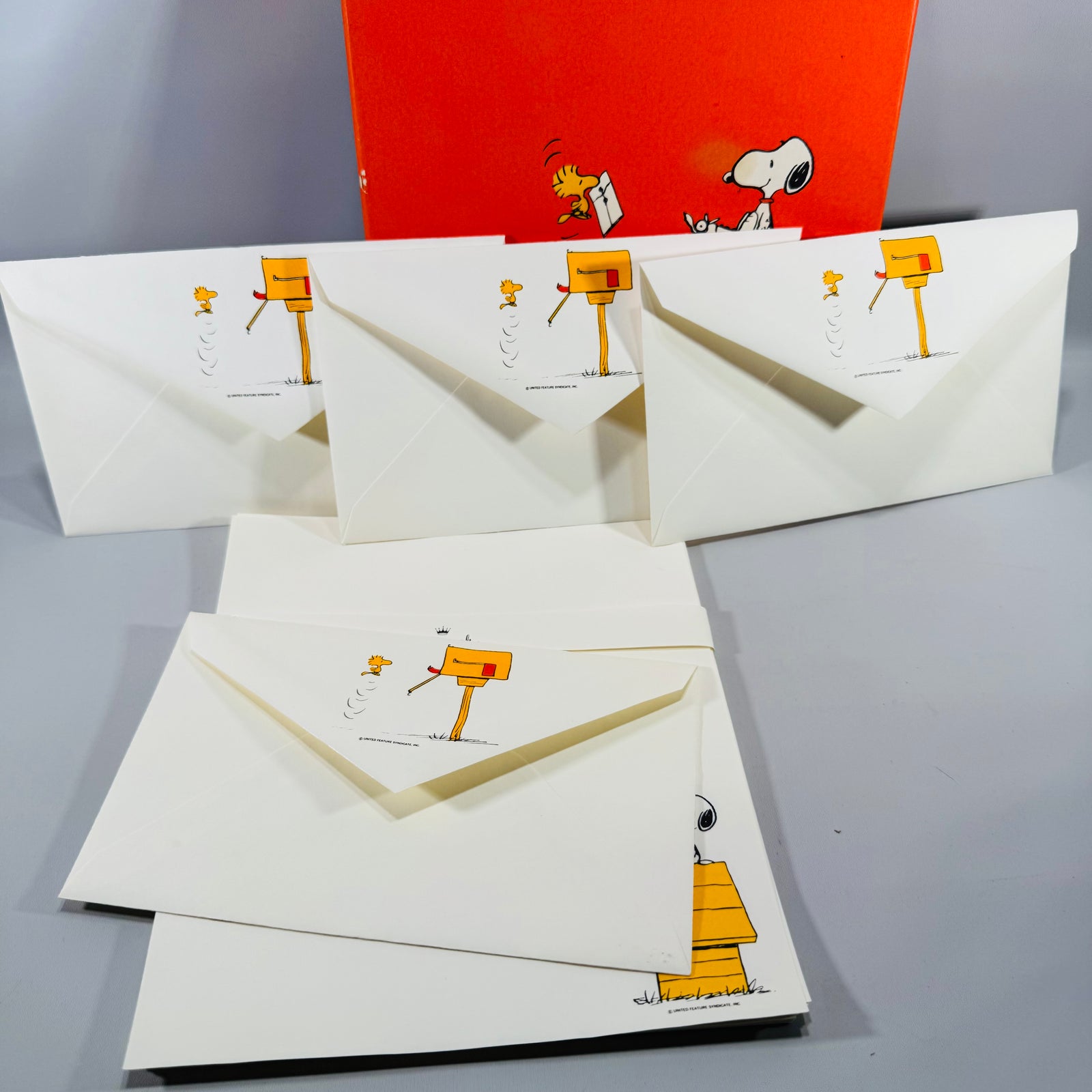 Vintage Hallmark Peanuts Snoopy and Woodstock stationery set with orange box, matching letter paper and envelopes shown in a tabletop display.