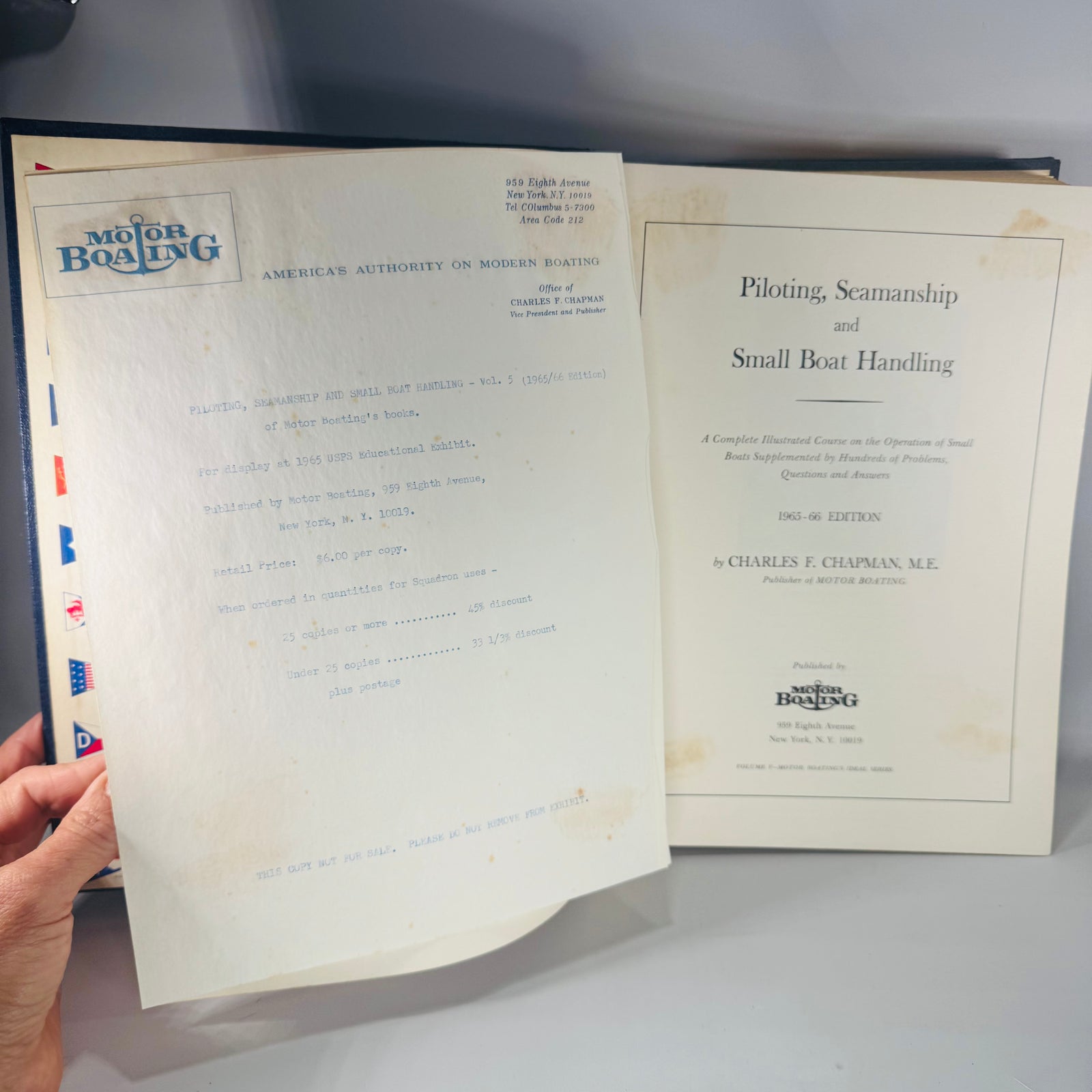 Navy blue hardcover vintage boating manual titled “Piloting, Seamanship and Small Boat Handling” by Charles F. Chapman, with interior photos of nautical charts and seamanship spreads.