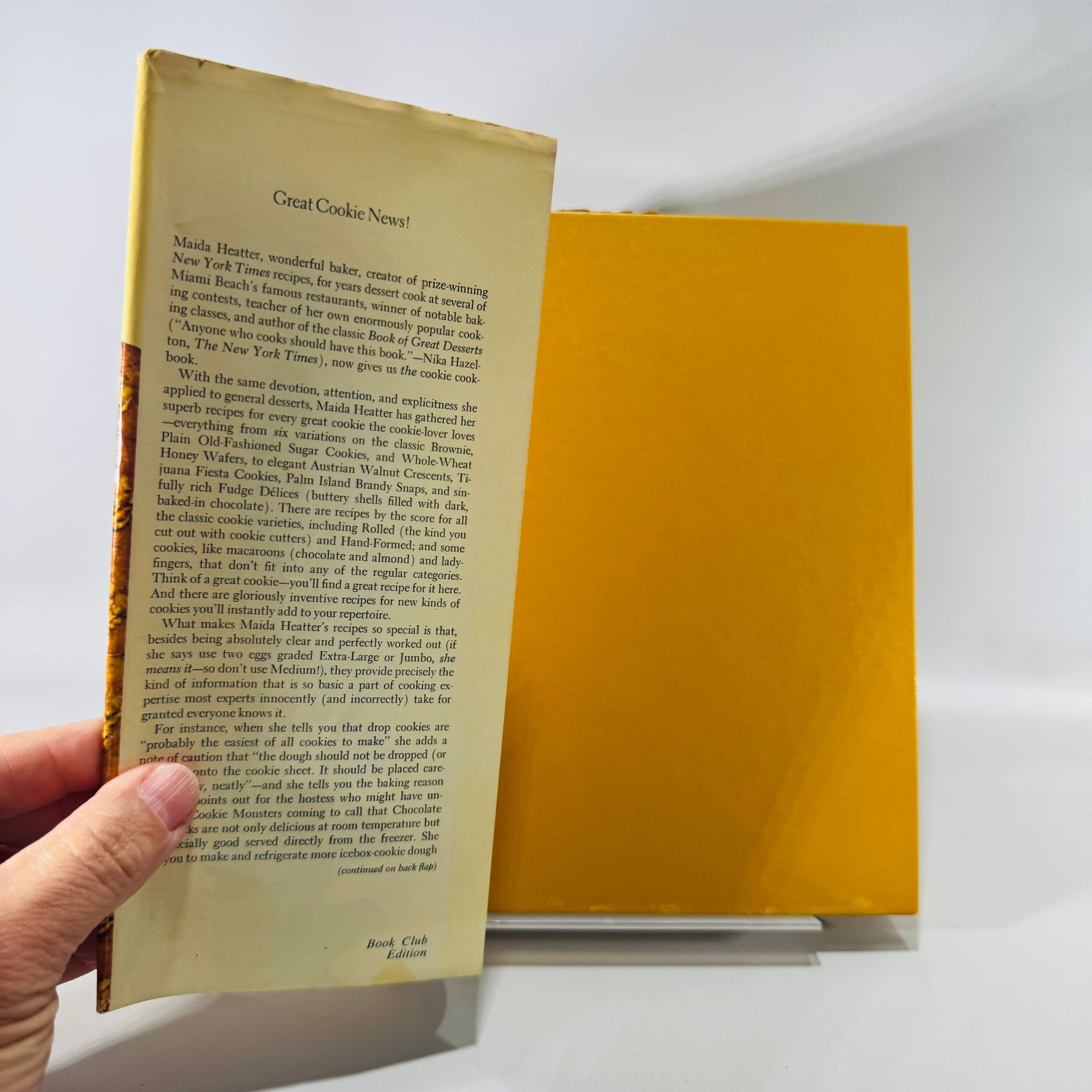 Vintage cookbook of “Maida Heatter’s Book of Great Cookies” with a cream/yellow dust jacket, bold red “COOKIES” title, and a row of assorted cookies pictured along the bottom