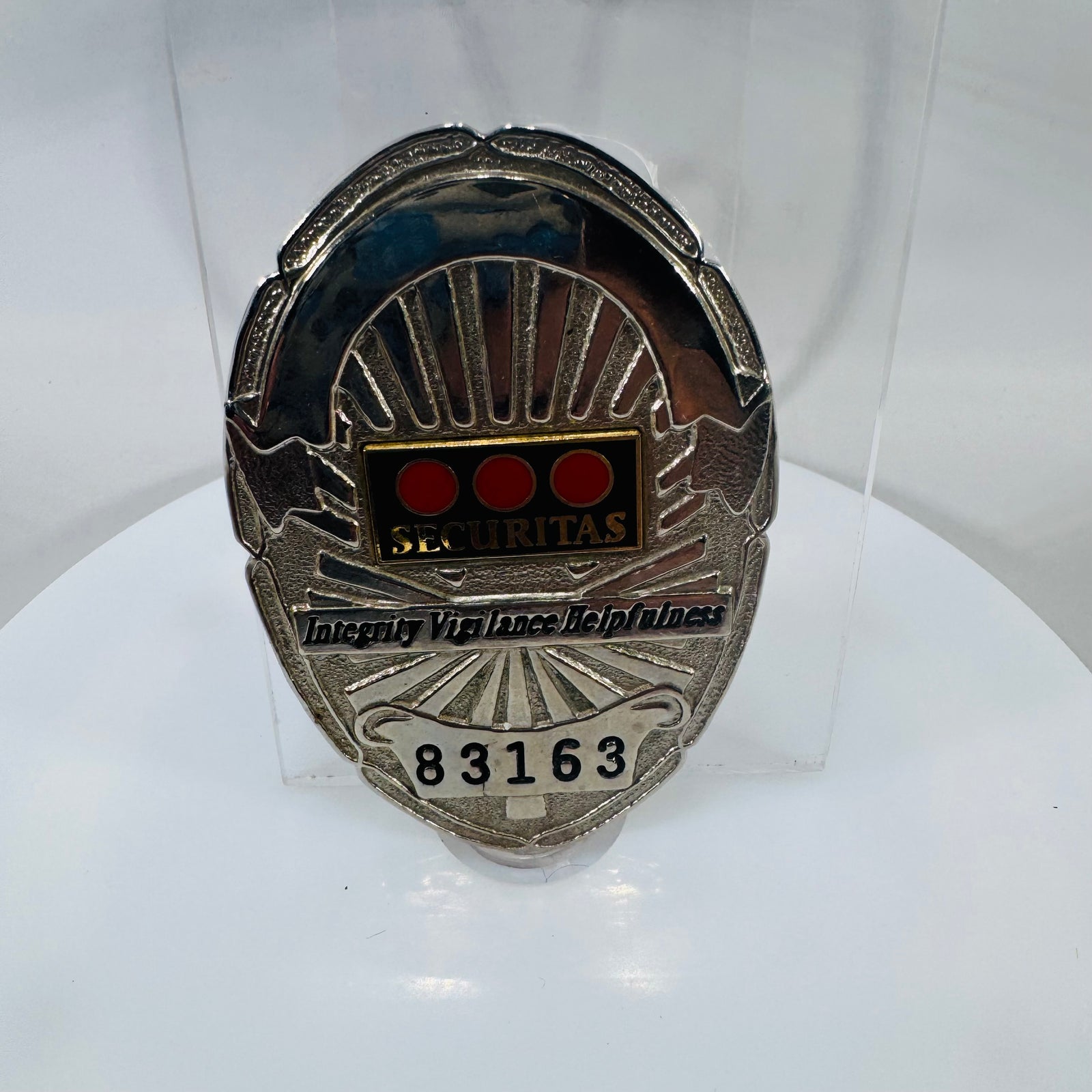  a silver-tone vintage Securitas security badge with three red-dot enamel logo, “SECURITAS” lettering, motto, and badge number 83163.