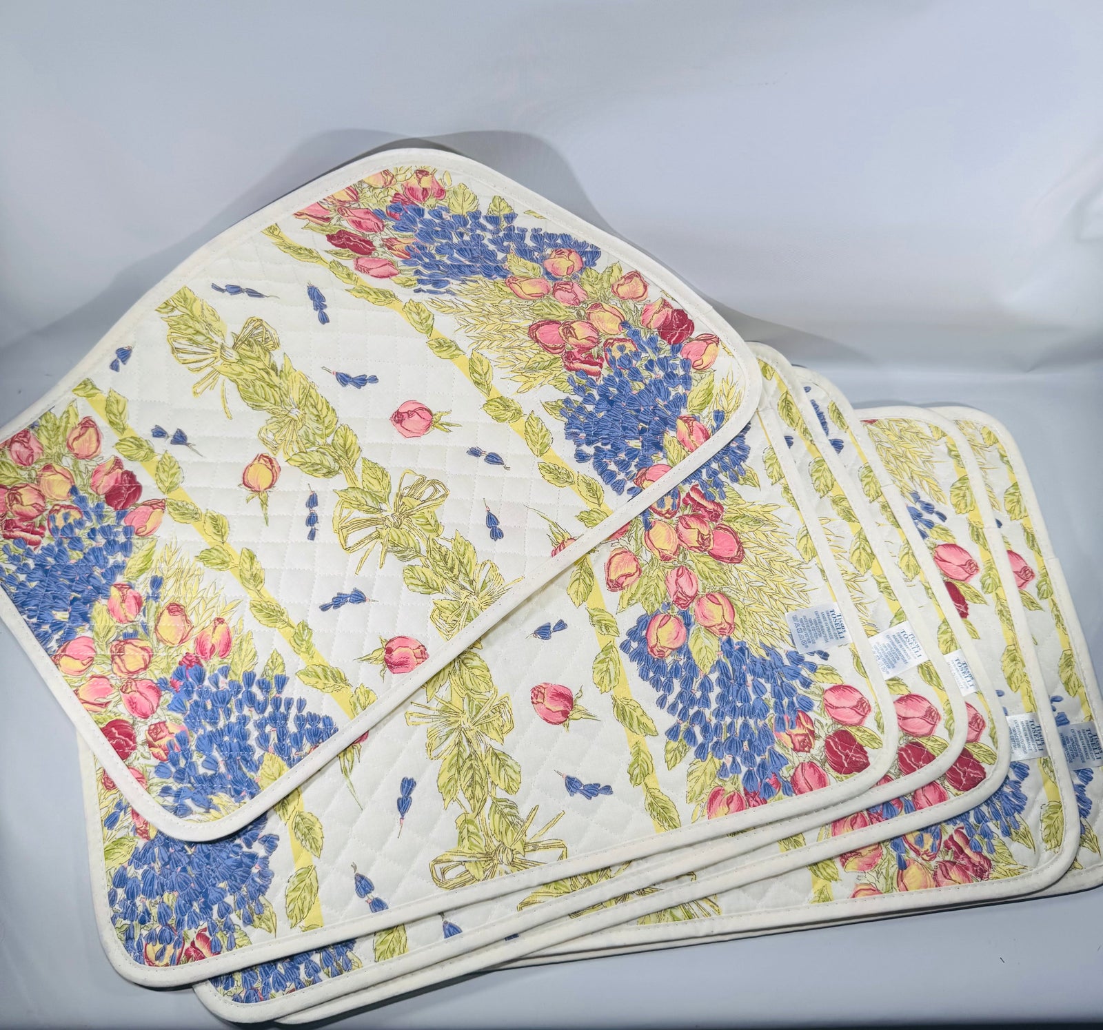 Set of six quilted Tissus Toselli placemats with French Provencal floral print—pink roses and blue lavender on white, made in France.