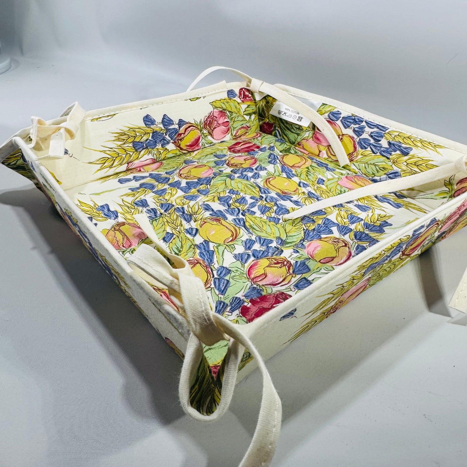 Square Tissus Toselli French Provencal bread basket in Rose & Lavender (Rose Lavande) floral print, laid flat with corner ties on a white background.