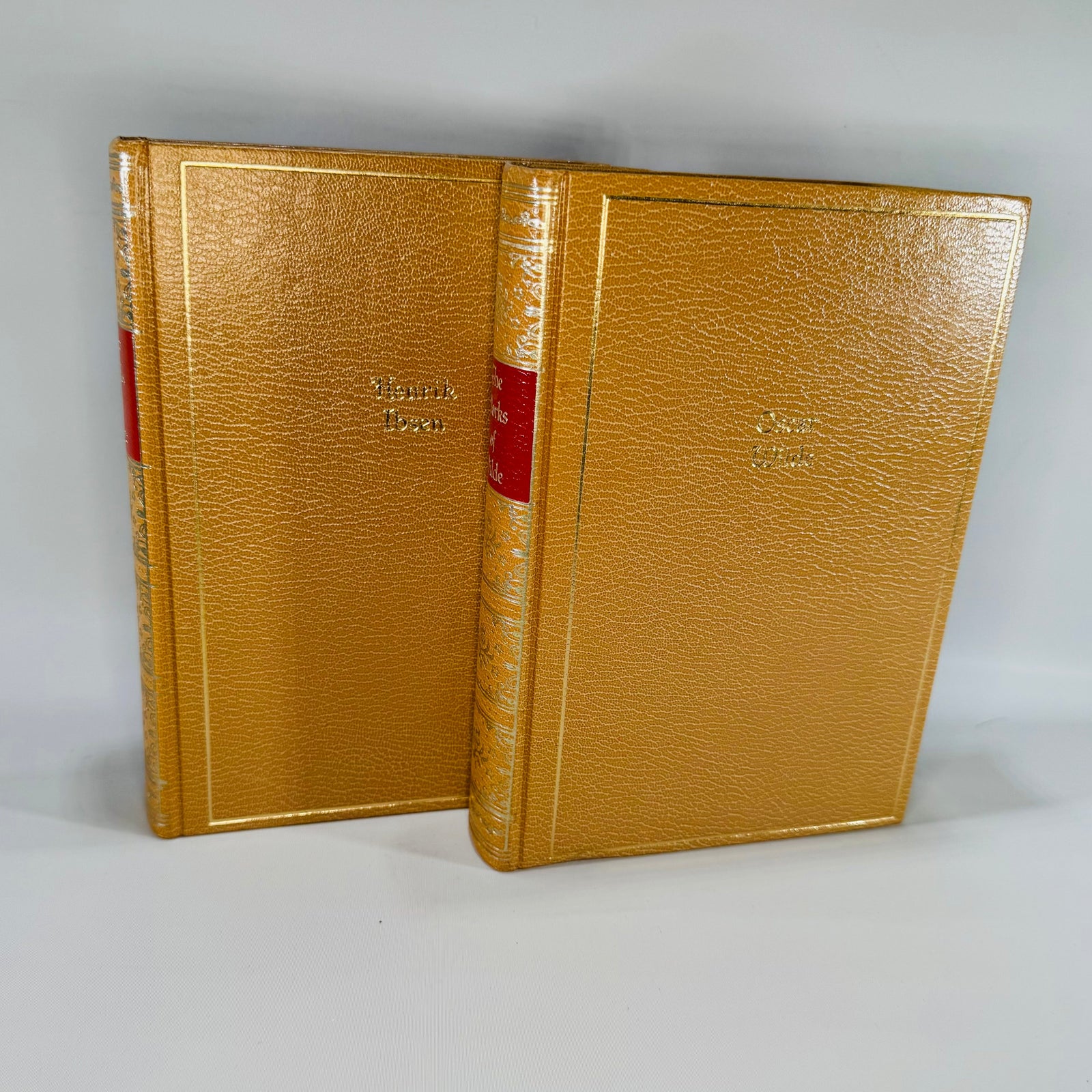 Two gold-bound books with red bands on a gray background