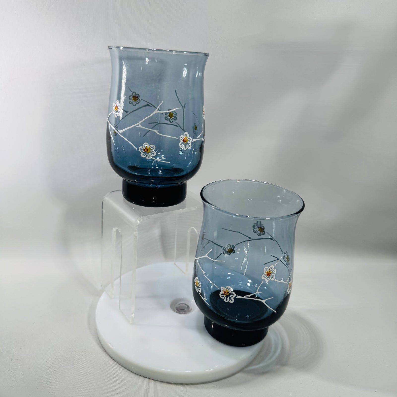 Two vintage Libbey smoky blue dogwood tumblers with white branch and floral design, 5 inches tall with darker blue weighted base.