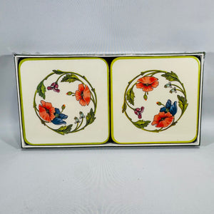 Villeroy & Boch Amapola porcelain coasters in a box, cream background with green border and a floral wreath of red poppies and blue flowers.