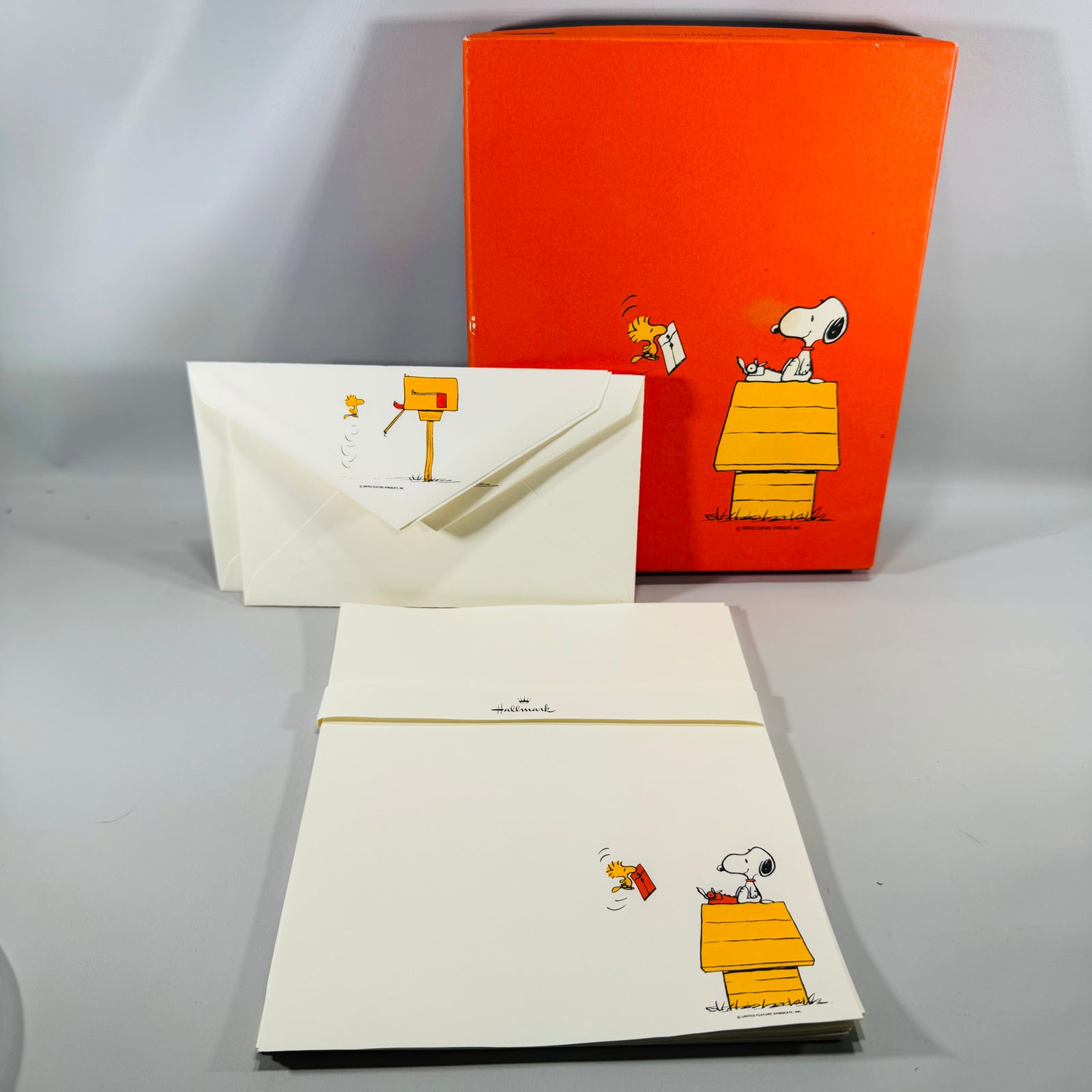 Vintage Hallmark Peanuts Snoopy and Woodstock stationery set with orange box, matching letter paper and envelopes shown in a tabletop display.