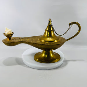 Vintage etched brass Aladdin-style genie lamp with chain-attached lid and wick cup, photographed on a white background.