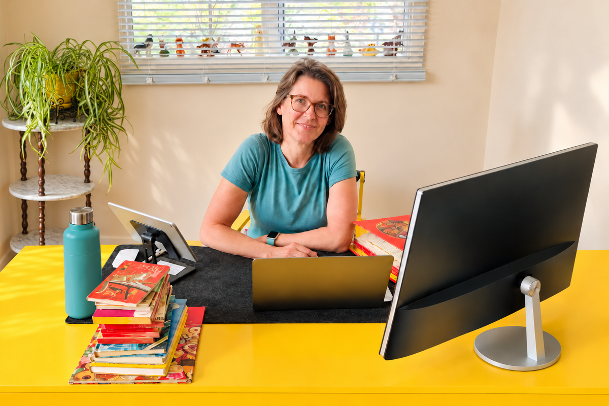 Pam Fournier, owner of Reading Vintage, at her desk with a stack of vintage books