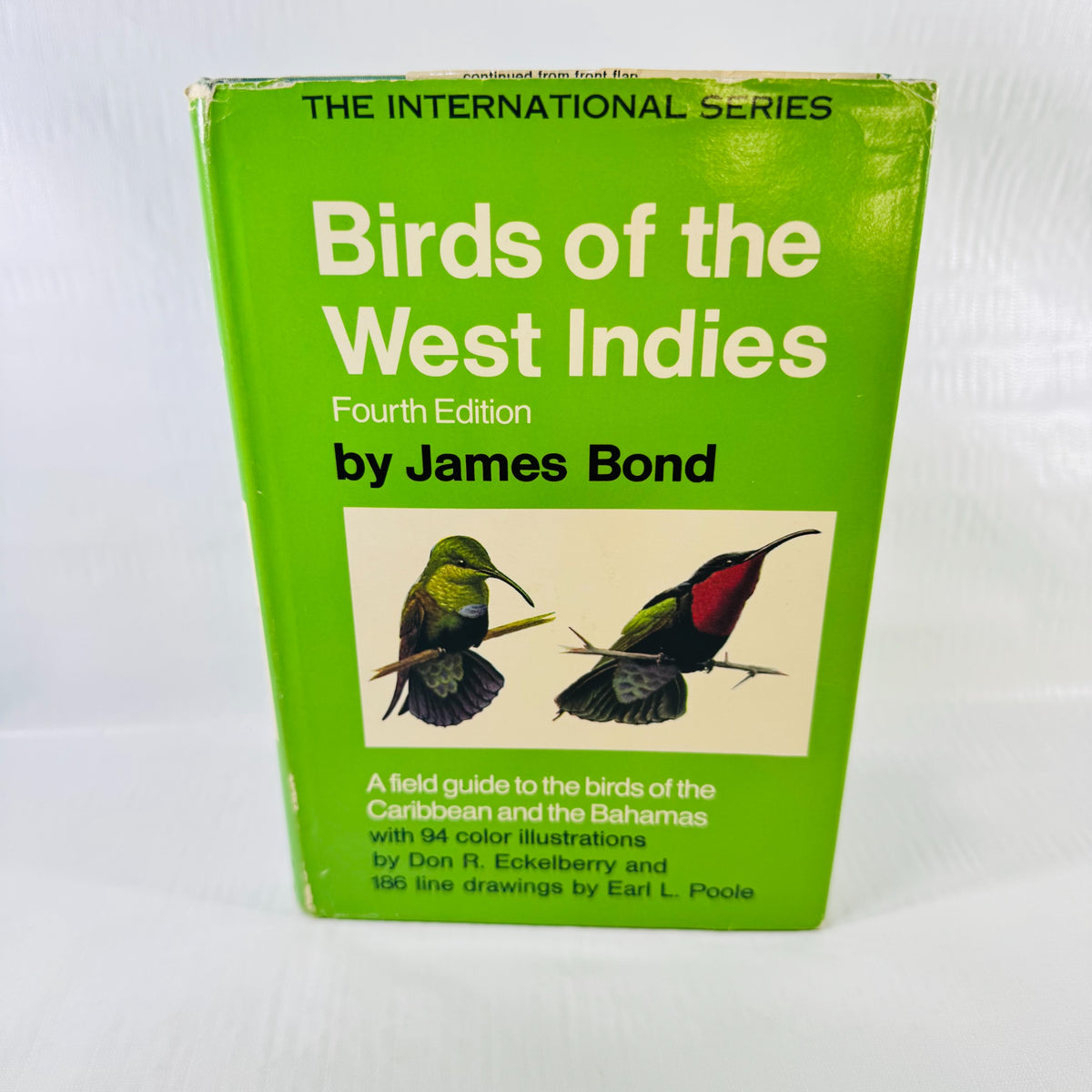 Front dust jacket of Birds of the West Indies by James Bond, Fourth Edition, with green background, two illustrated birds, and visible edge wear.