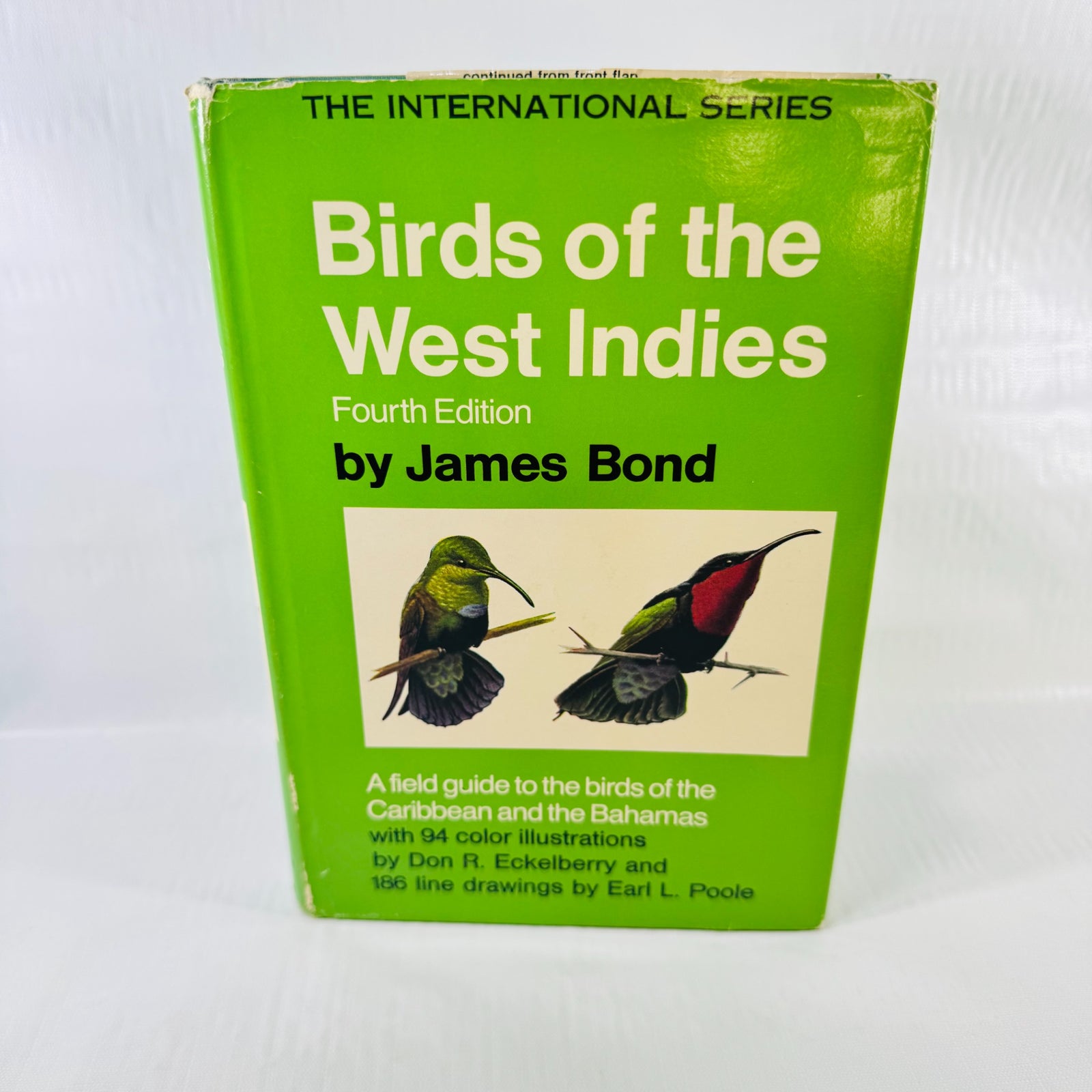 Front dust jacket of Birds of the West Indies by James Bond, Fourth Edition, with green background, two illustrated birds, and visible edge wear.