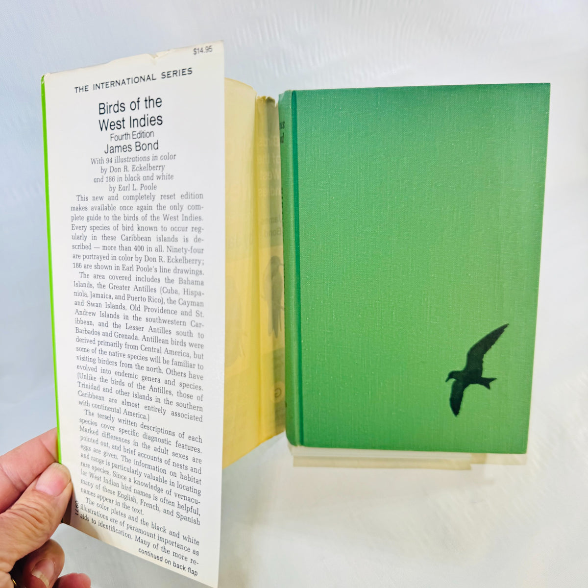 Green cloth front cover of Birds of the West Indies with a black bird silhouette beside the open dust jacket flap showing the $14.95 price.