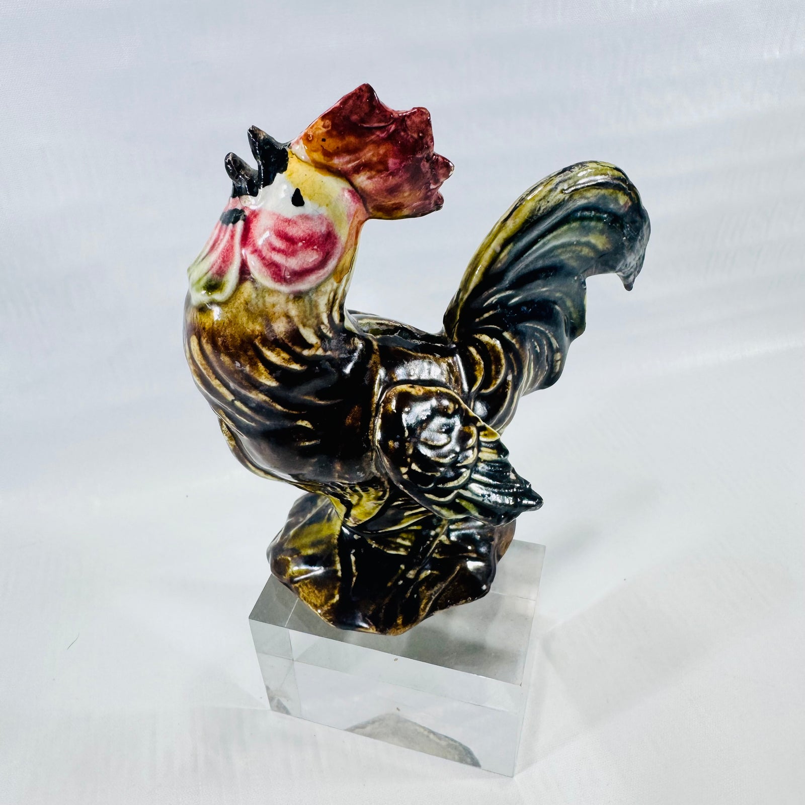 Other side of the ceramic rooster coin bank standing on its molded rock base.
