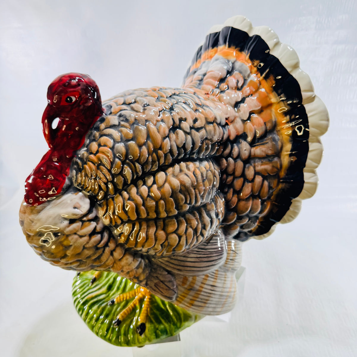 Side view of a glazed ceramic tom turkey with fanned tail and yellow feet